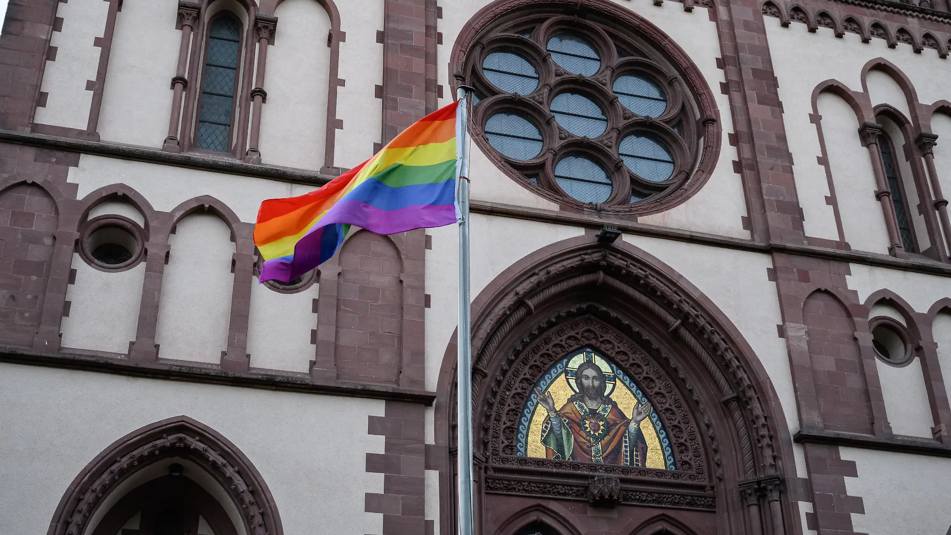 Eine Regenbogenfahne vor der Herz-Jesu-Kirche in Freiburg im Breisgau.