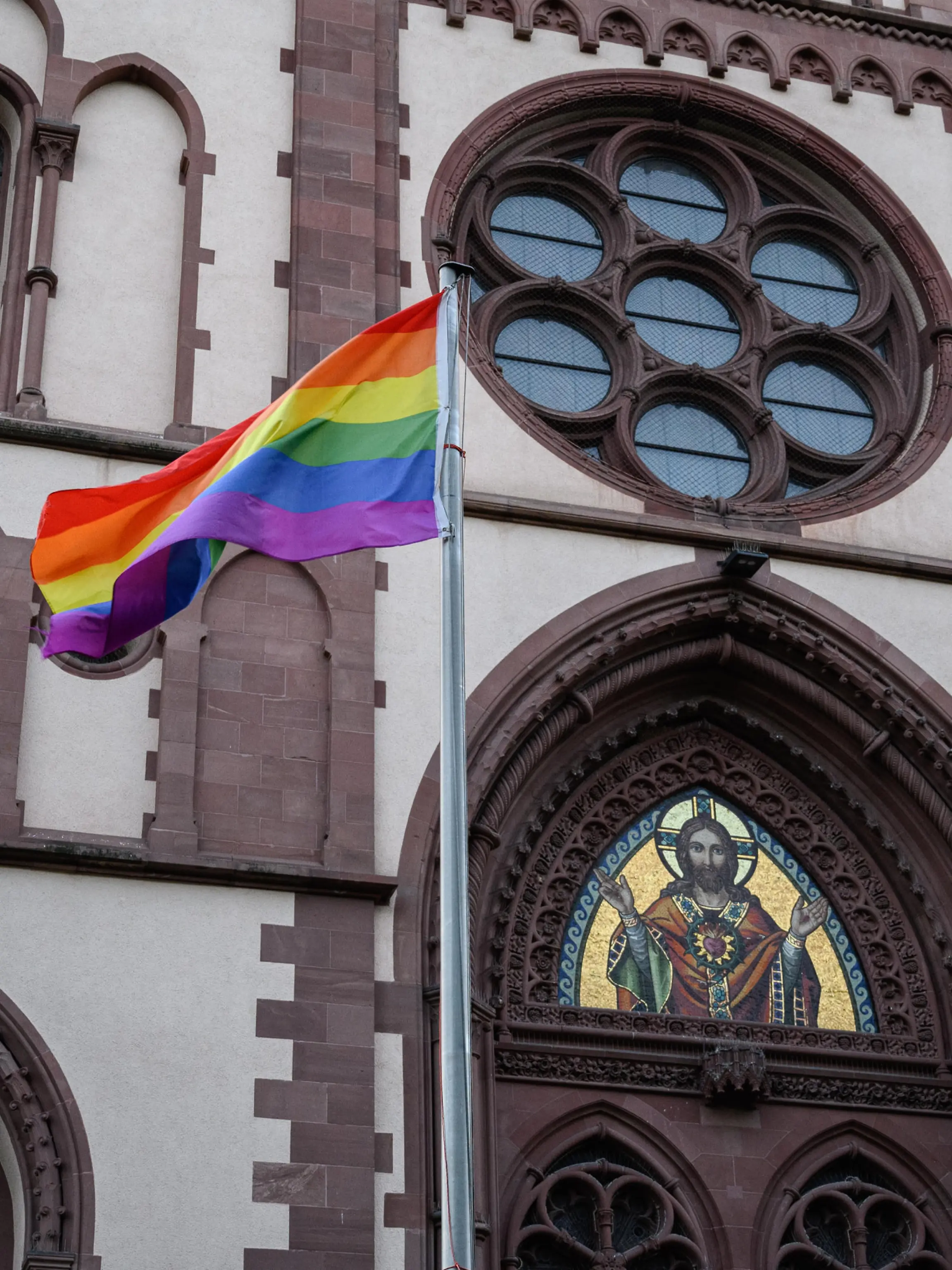 Eine Regenbogenfahne vor der Herz-Jesu-Kirche in Freiburg im Breisgau.