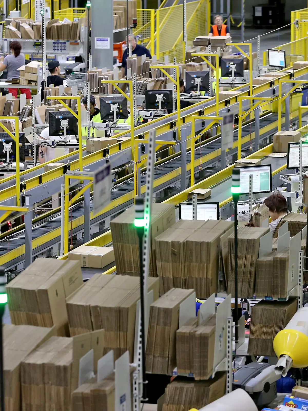 Mitarbeiter des Amazon-Logistikzentrums in Leipzig (Sachsen) verpacken am 19.11.2015 Waren für den Paketversand. Für den Online-Versandhändler mit seinen über zwei Millionen Kunden weltweit beginnt jetzt das Weihnachtsgeschäft. Im Versandzentrum Leipzig beschäftigt Amazon derzeit rund 2700 Mitarbeiter. Foto: Jan Woitas/dpa