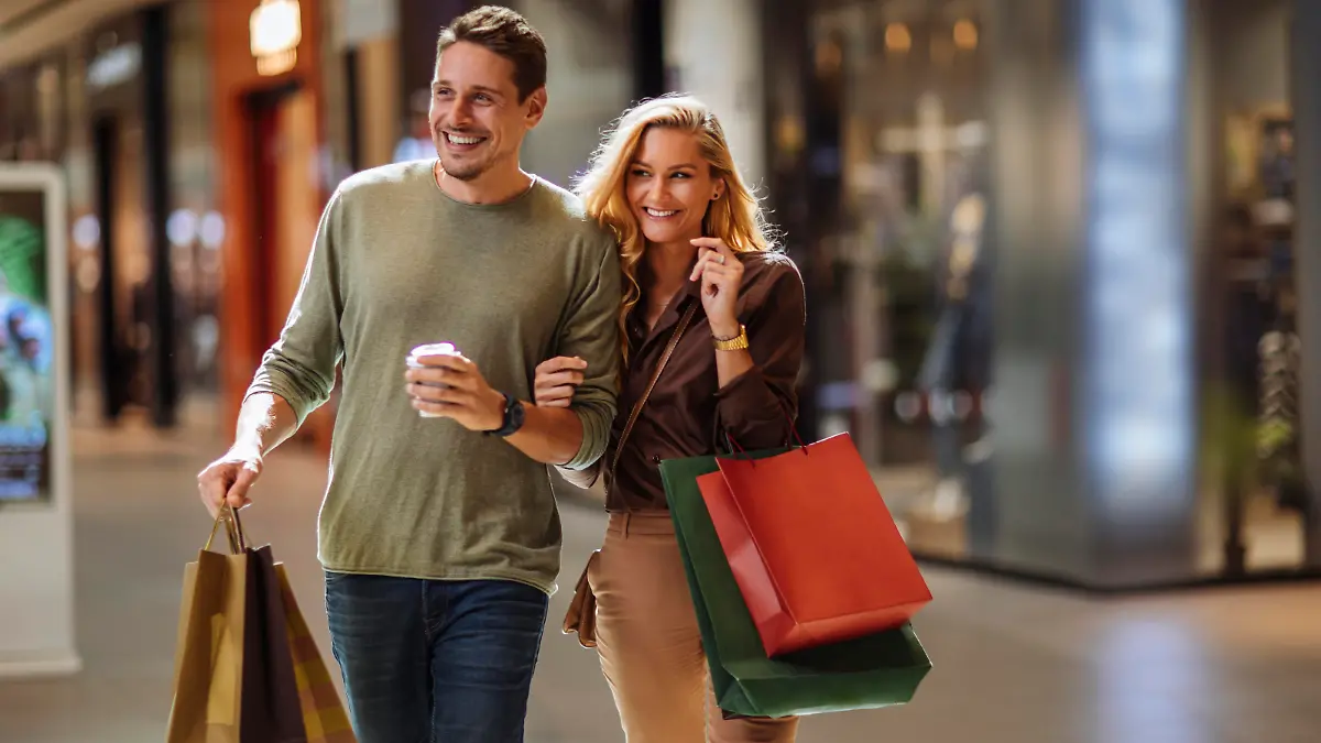 Smiling young couple walking through the mall after some shopping