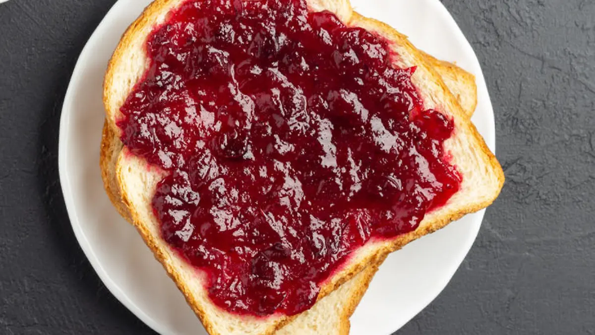 Wheat bread toast with cranberry jam on dark slate background. Above view.