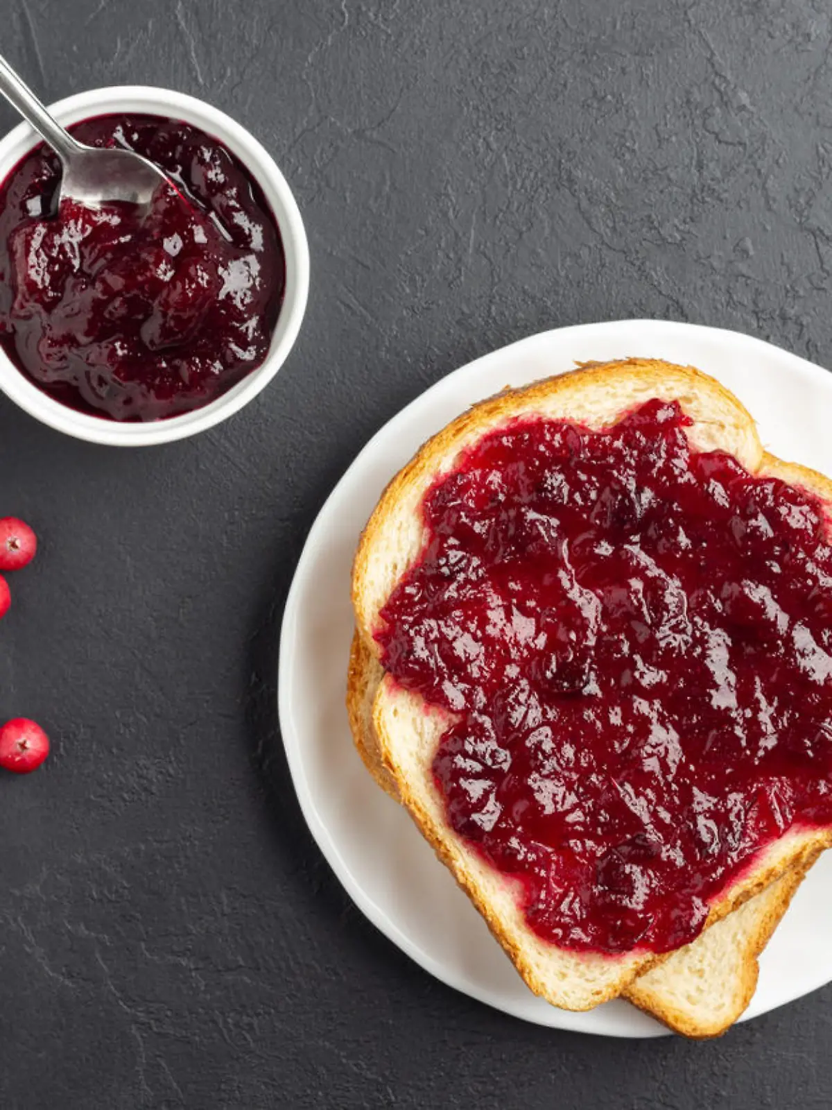 Wheat bread toast with cranberry jam on dark slate background. Above view.