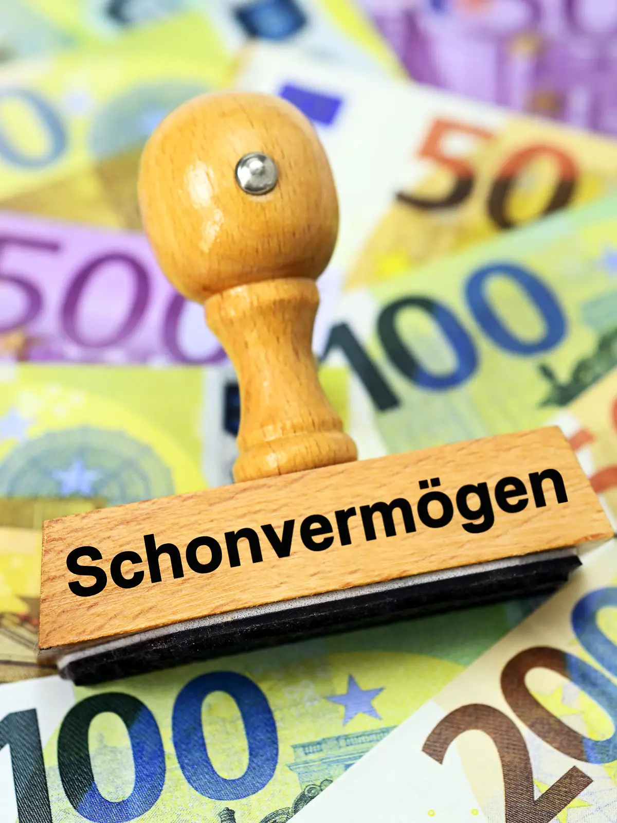 Stempel mit Aufschrift Schonvermögen auf Geldscheinen / action press