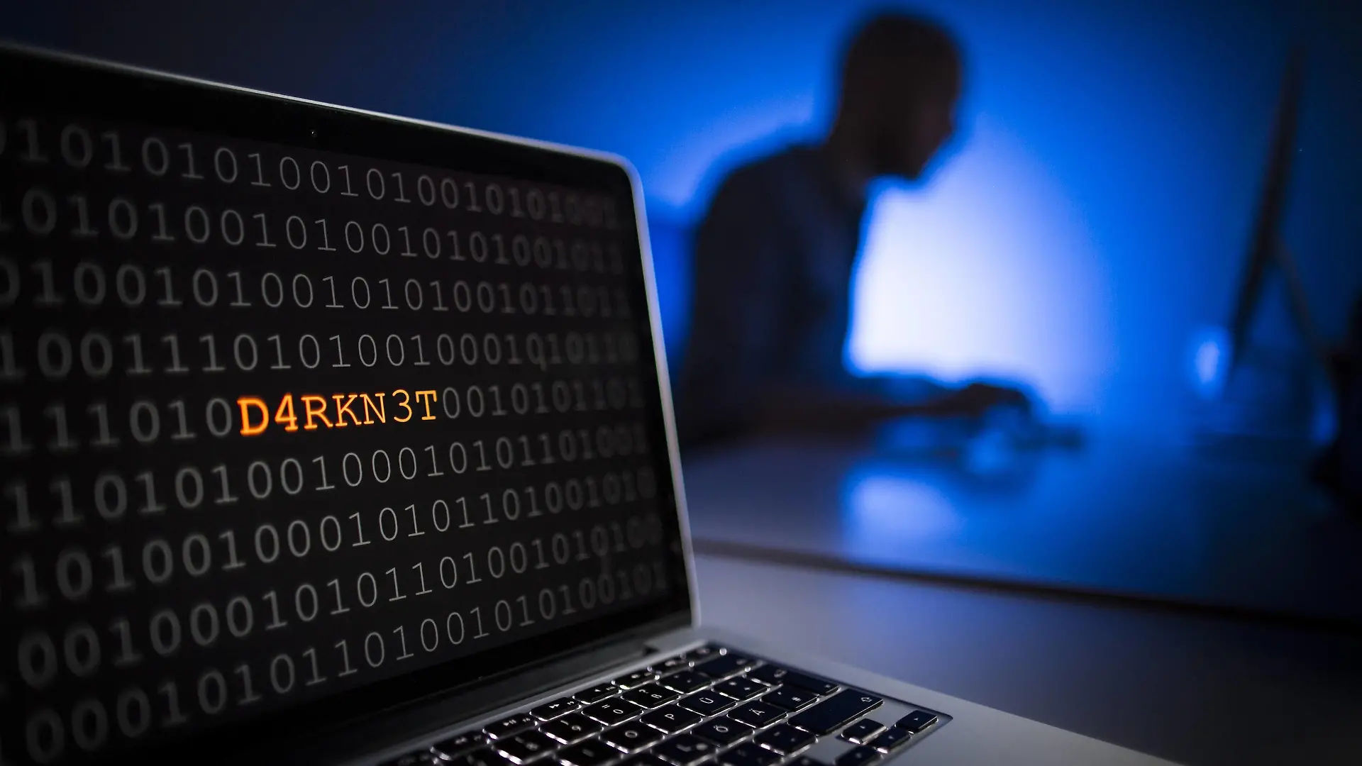 Illustration zum Thema Darknet . Nahaufnahme eines Laptops mit Binaercode. Im Hintergrund sitzt ein Mann an einem Computer, Berlin, 13.01.2017. MODEL RELEASE vorhanden, Model release available, MODEL RELEASED, Berlin Deutschland PUBLICATIONxINxGERxSUIxAUTxONLY Copyright: xFlorianxGaertnerx