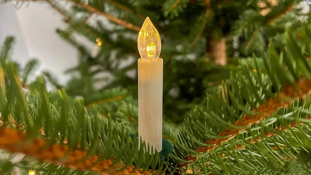 A plastic candle on a Christmas tree.