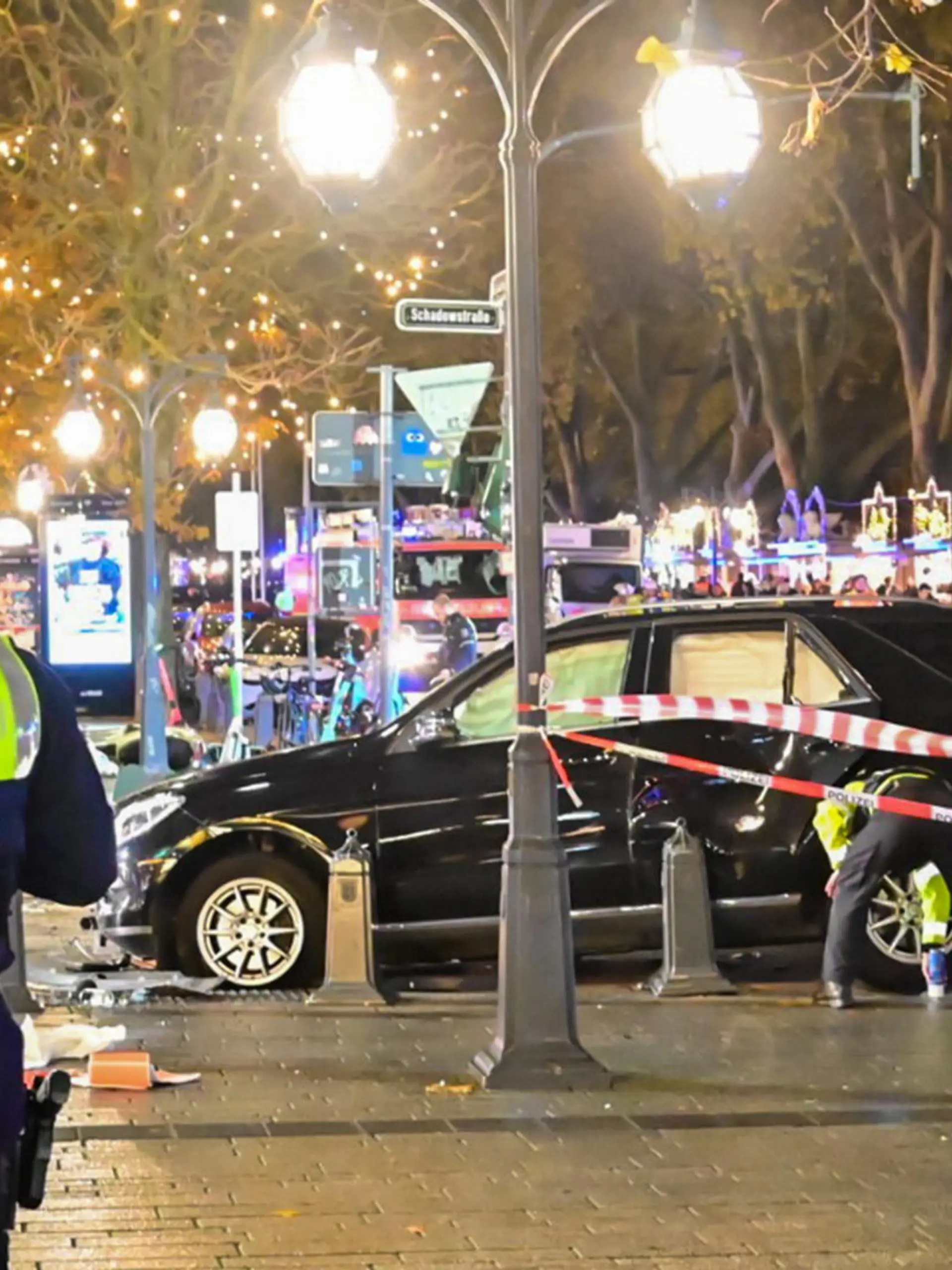 22.11.2022, Nordrhein-Westfalen, Düsseldorf: Flatterband sichert die Unfallstelle rund um ein Auto auf der Königsallee. Auf der Düsseldorfer Einkaufsmeile hat es unweit des Weihnachtsmarktes einen Autounfall mit zwei Schwerverletzten gegeben. Ein 84-Jähriger habe am frühen Dienstagabend die Kontrolle über sein Auto verloren und sei dann in parkende E-Scooter gefahren, sagte ein Polizei-Sprecher. Zwei Fußgänger wurden schwer verletzt, Lebensgefahr bestand den Angaben zufolge bei ihnen aber zufolge nicht. Foto: Alex Forstreuter/dpa +++ dpa-Bildfunk +++