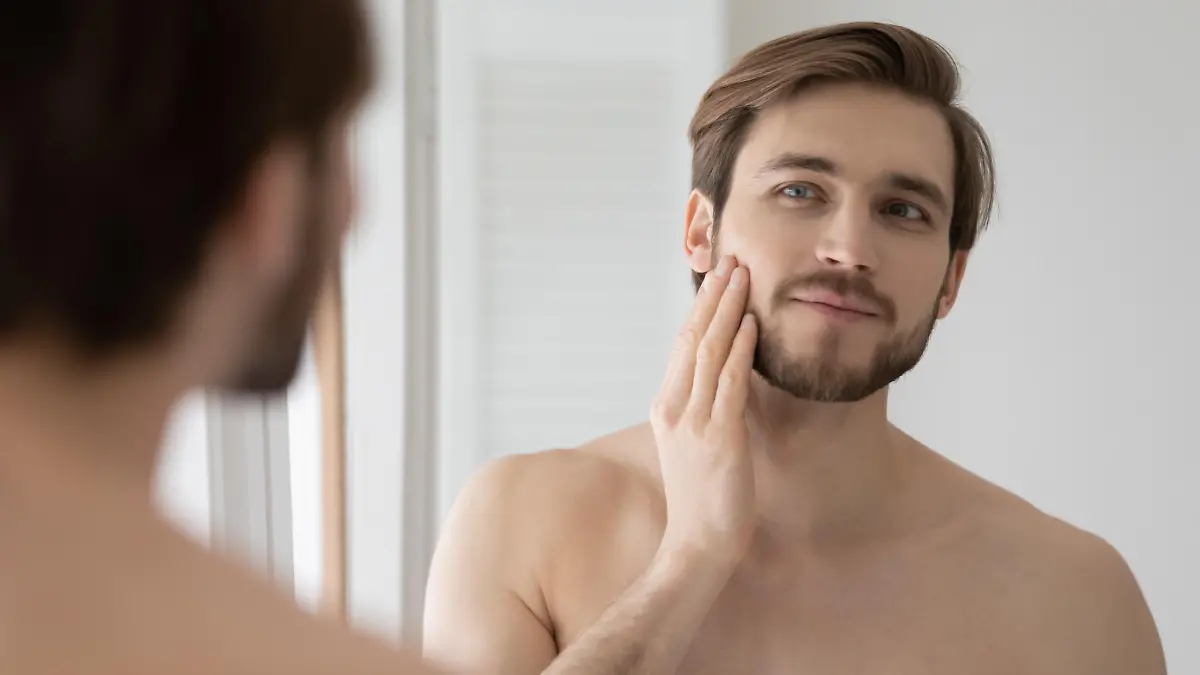 Young shirtless man looking in mirror touch his face after shave applied aftershave cream enjoy smooth, flawless, soft skin. Grooming, morning routine, ad of skincare cosmetic products for men concept Model Released Property Released xkwx 30s, aftershave, shaving, anti, aging, antiage, check, beauty, care, clean, cosmetics, cream, bearded, bathroom, enjoy, young, wrinkle, touch, soft, skin, skincare, smooth, shirtless, refreshment, rejuvenation, reflection, product, prevention, personal, person, peeling, one, morning, moisturizer, mirror, man, face, facial, fresh, grooming, handsome, health, healthy, hydrated, hygiene, looking, lotion, lifestyle, dermatology, routine