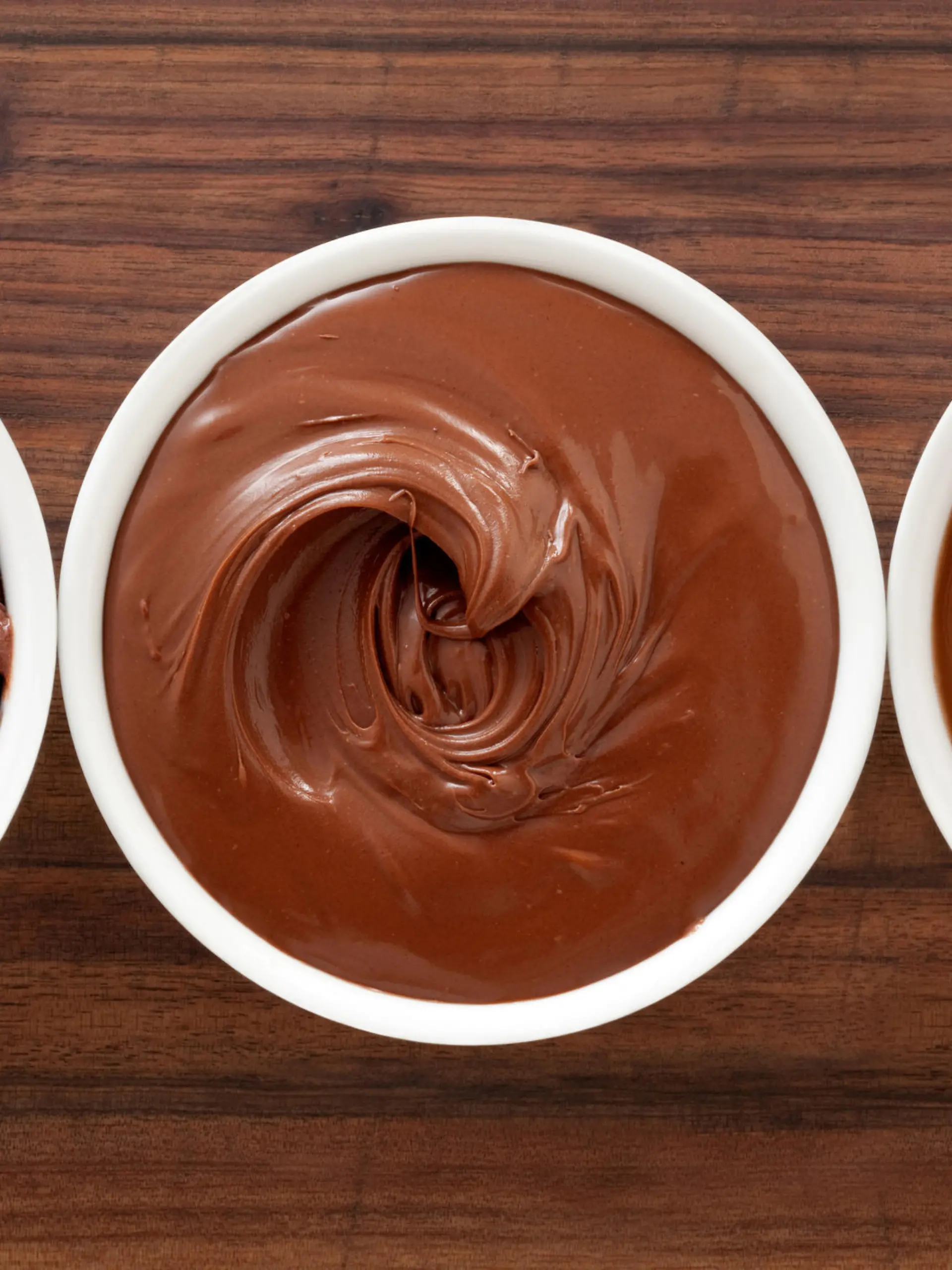 Three bowls containing soft chocolate stuff (mousse, spread and pudding)