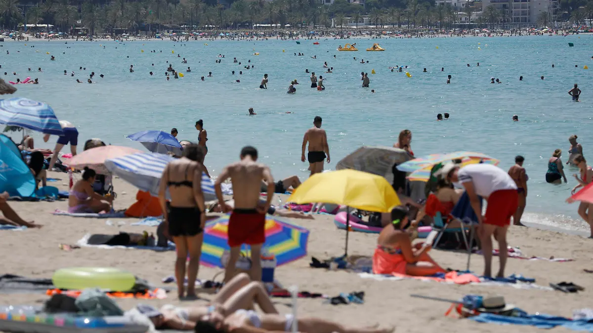 21.07.2022, Spanien, Palma: Menschen liegen am Strand von Arenal auf Mallorca in der Sonne, während andere sich im Wasser abkühlen. Auf Mallorca wurde schon vor Jahren eine «Qualitätsoffensive» gestartet. Trotzdem wird auf der liebsten Insel der Deutschen immer noch so wild Party gemacht wie eh und je. Nun wird von den Behörden erstmals wirklich hart durchgegriffen. (Zu dpa "Mallorca bekämpft Alkoholexzesse und Frauen-Demütigung: «Basta»") Foto: Clara Margais/dpa +++ dpa-Bildfunk +++