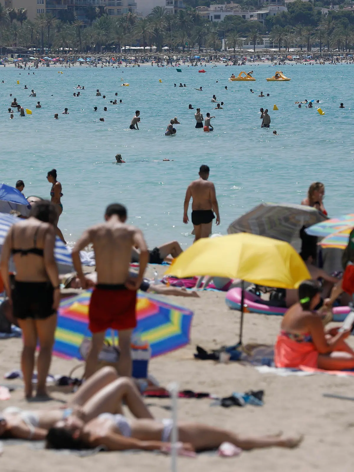 21.07.2022, Spanien, Palma: Menschen liegen am Strand von Arenal auf Mallorca in der Sonne, während andere sich im Wasser abkühlen. Auf Mallorca wurde schon vor Jahren eine «Qualitätsoffensive» gestartet. Trotzdem wird auf der liebsten Insel der Deutschen immer noch so wild Party gemacht wie eh und je. Nun wird von den Behörden erstmals wirklich hart durchgegriffen. (Zu dpa "Mallorca bekämpft Alkoholexzesse und Frauen-Demütigung: «Basta»") Foto: Clara Margais/dpa +++ dpa-Bildfunk +++