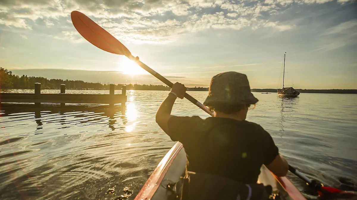  Eine Frau fährt mit ihrem Kajak auf dem Starnberger See dem Sonnenuntergang entgegenan, Starnberg, Bayern, Deutschland. Eine Frau paddelt auf einer Kajaktour auf dem Starnberger See