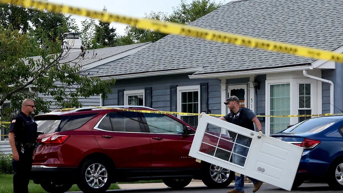 18.09.2023, USA, Romeoville: Ein Polizeibeamter aus Romeoville trägt eine Tür aus dem Inneren des Hauses heraus, in dem vier Menschen erschossen wurden. Foto: Stacey Wescott/Chicago Tribune/AP - ACHTUNG: Nur zur redaktionellen Verwendung und nur mit vollständiger Nennung des vorstehenden Credits +++ dpa-Bildfunk +++