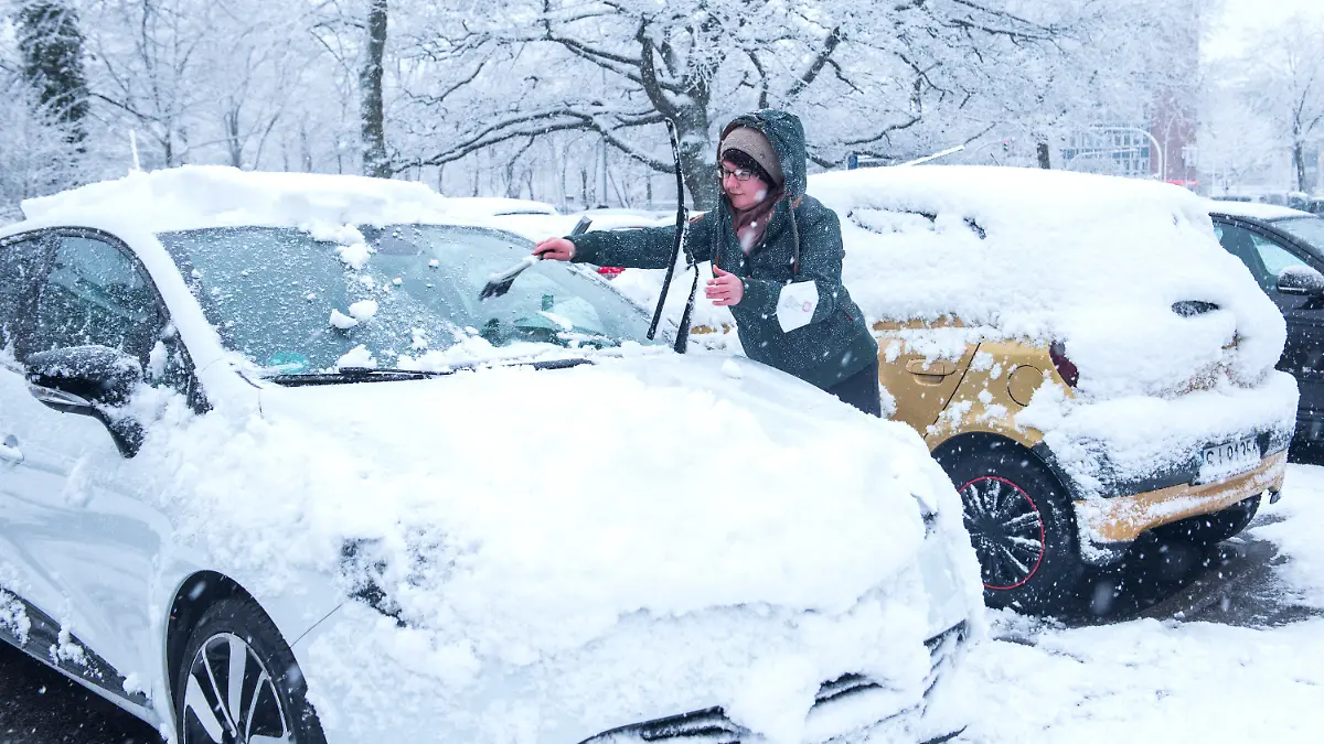 31.03.2022, Hamburg: Eine Frau reinigt bei Schneefall ihr Auto. Foto: Daniel Bockwoldt/dpa +++ dpa-Bildfunk +++