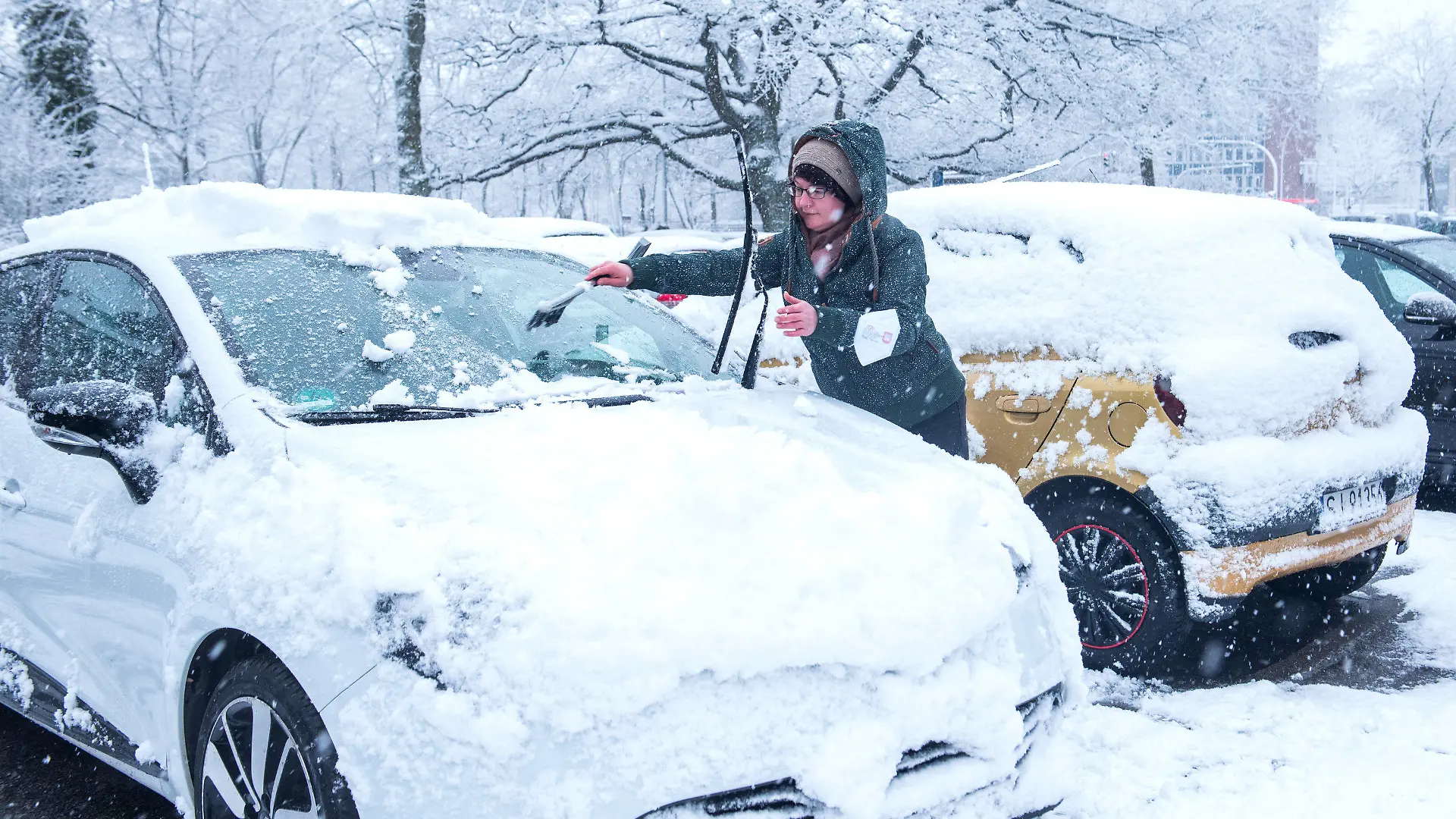 31.03.2022, Hamburg: Eine Frau reinigt bei Schneefall ihr Auto. Foto: Daniel Bockwoldt/dpa +++ dpa-Bildfunk +++
