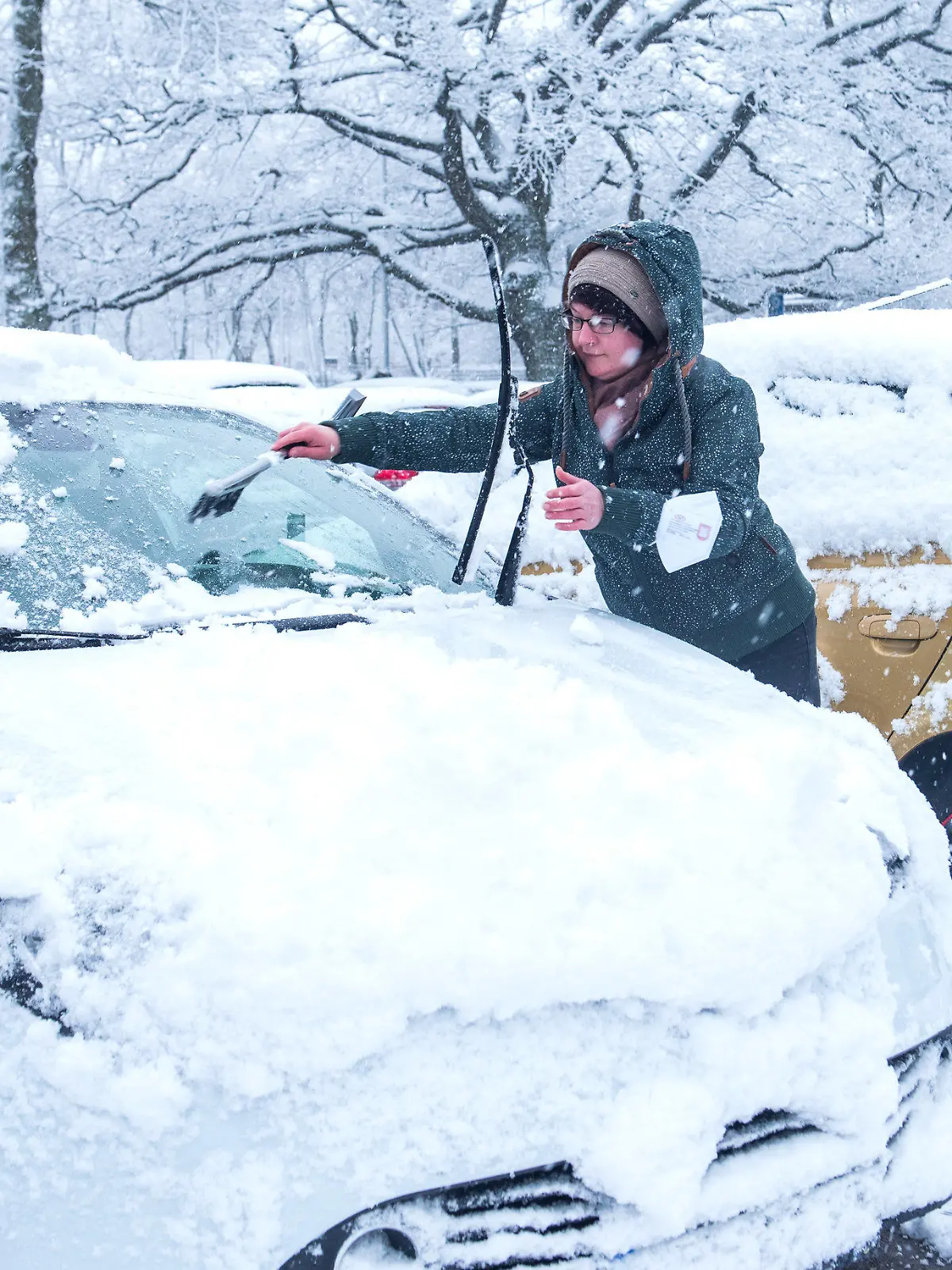31.03.2022, Hamburg: Eine Frau reinigt bei Schneefall ihr Auto. Foto: Daniel Bockwoldt/dpa +++ dpa-Bildfunk +++