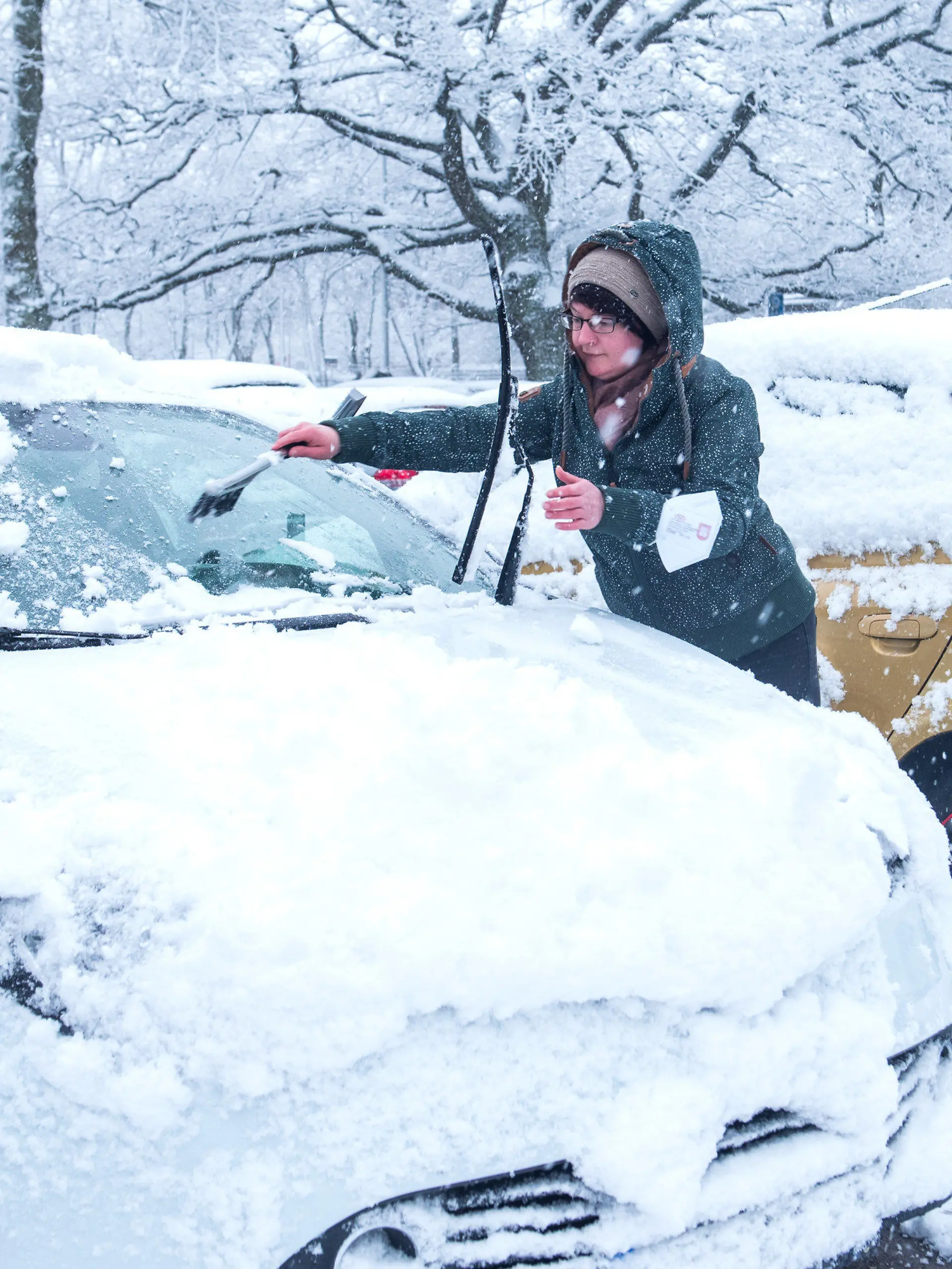 31.03.2022, Hamburg: Eine Frau reinigt bei Schneefall ihr Auto. Foto: Daniel Bockwoldt/dpa +++ dpa-Bildfunk +++