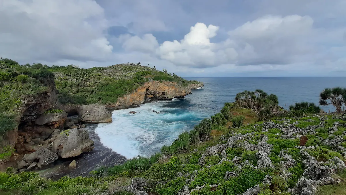 View from the hill edge on Midodaren beach east in high angle view. Waves crashing against sand beach in Java, Indonesia