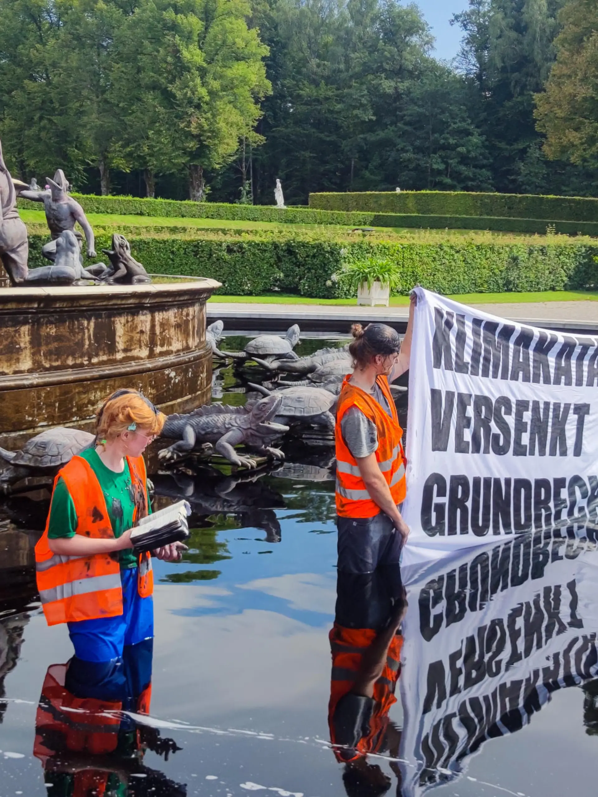 Aktivisten der Letzten Generation stehen bei der Protestaktion am 23. August im Wasser des Latona-Brunnens in Herrenchiemsee.