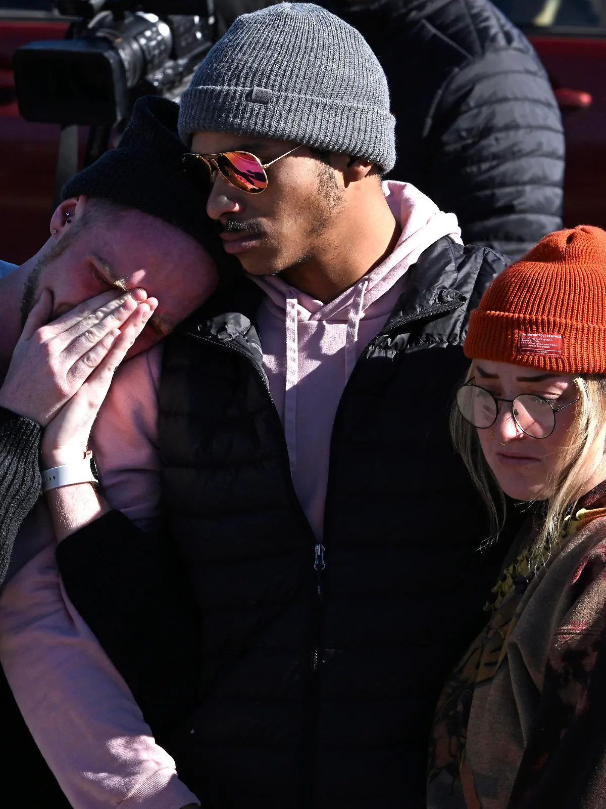 Tyler Johnston, left, his fiance Keenan Mestas-Holmes, center, and their friend Atlas Pretzeus hug one another while paying their respects at a makeshift memorial near Club Q on Sunday, Nov. 20, 2022 in Colorado Springs, Colo. The trio have close friends that were involved in the shooting. An attacker opened fire in a gay nightclub late Saturday night. (Helen H. Richardson/The Denver Post via AP)