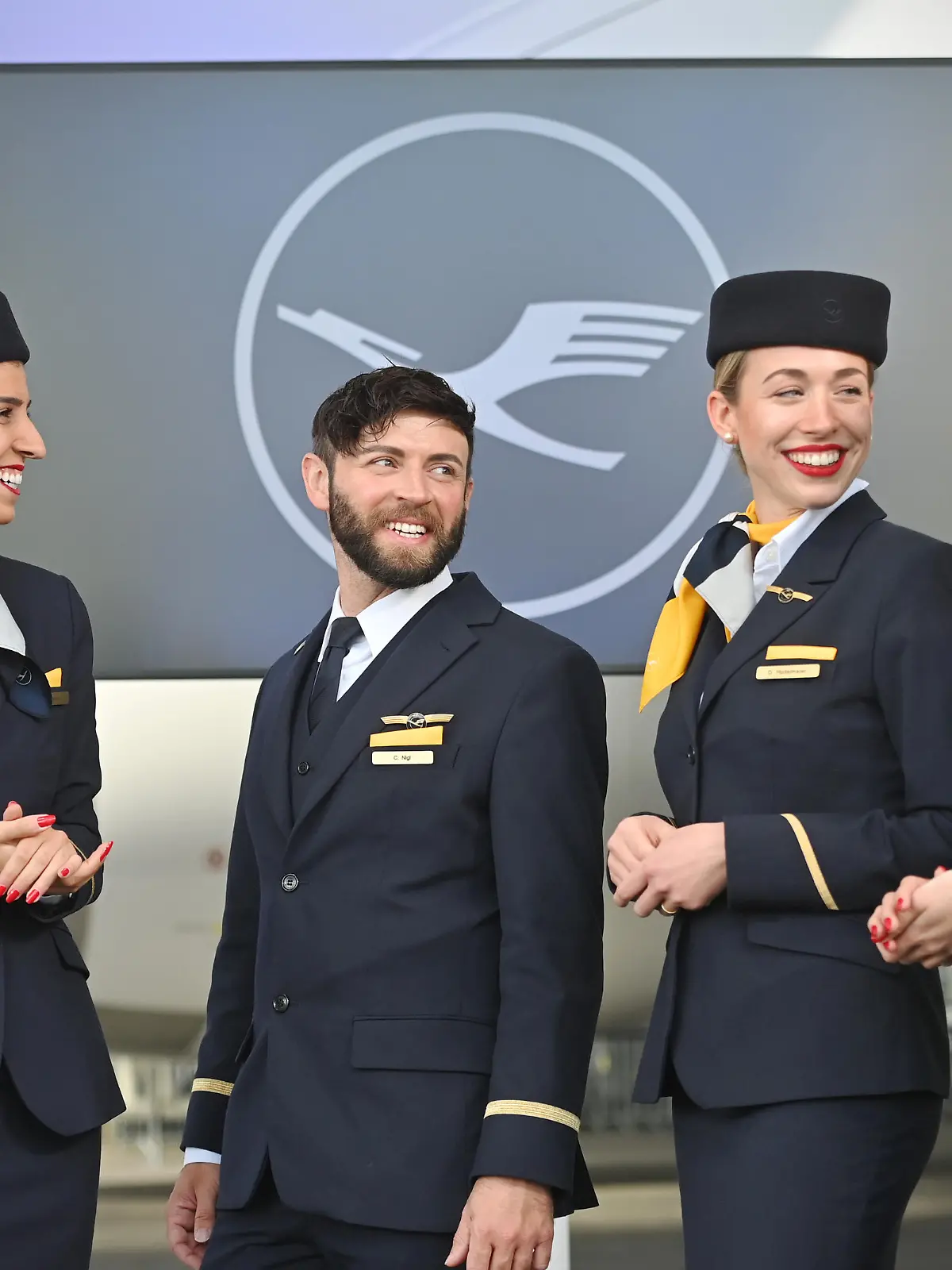 Flugbegleiter,Stewardess,Steward,Kabinenpersonal,lacht,lachen,lachend,optimistisch,gutgelaunt. Lufthansa Flugzeugtaufe Airbus A350 MUENCHEN am 29.04.2022 im Flugzeughangar Flight Operation Center am Flughafen Franz Josef Strauss in Muenchen.