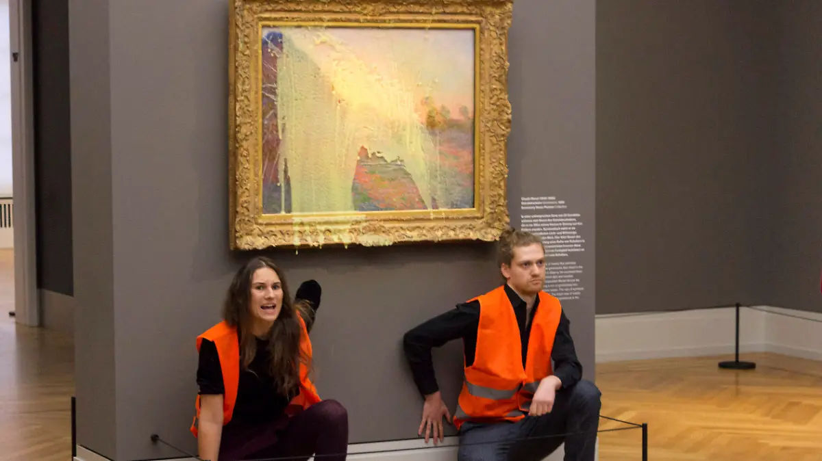 HANDOUT - 23.10.2022, Potsdam: Klimaaktivisten der Klimaschutz-Protestgruppe «Letzte Generation», nachdem sie das Gemälde «Getreideschober» (1890) von Claude Monet im Potsdamer Museum Barberini mit Kartoffelbrei beworfen haben. Nach der Attacke gegen das Gemälde «Getreideschober» (1890) von Claude Monet im Potsdamer Museum Barberini sind die beschuldigten Klimaaktivisten wieder auf freiem Fuß. (zu dpa: «Attacke gegen Monet-Bild: Aktivisten aus Gewahrsam entlassen») Foto: Uncredited/Letzte Generation/AP/dpa - ACHTUNG: Nur zur redaktionellen Verwendung im Zusammenhang mit der aktuellen Berichterstattung über die Aktion und nur mit vollständiger Nennung des vorstehenden Credits. Keine Verwendung nach dem 06.11.2022!! +++ dpa-Bildfunk +++