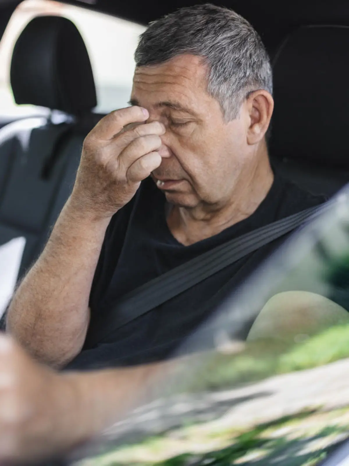 Tired pensioner in his 70s, dring in a car