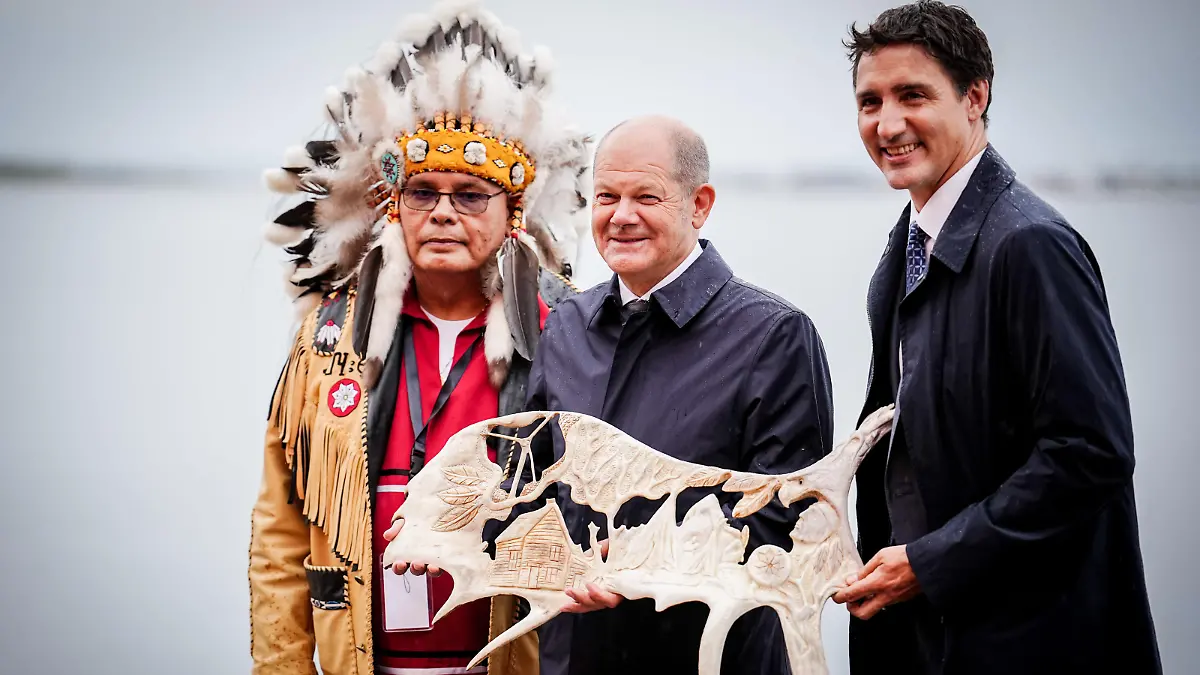 Bundeskanzler Olaf Scholz (M, SPD) und Justin Trudeau (r), Premierminister von Kanada, stehen mit Misel Joe, dem Chief der Ersten Nation Miawpukek, auf Neufundland mit einem verzierten Elchgeweih zusammen. Im Mittelpunkt der Reise steht die Zusammenarbeit beider Länder im Klima- und Energiebereich.