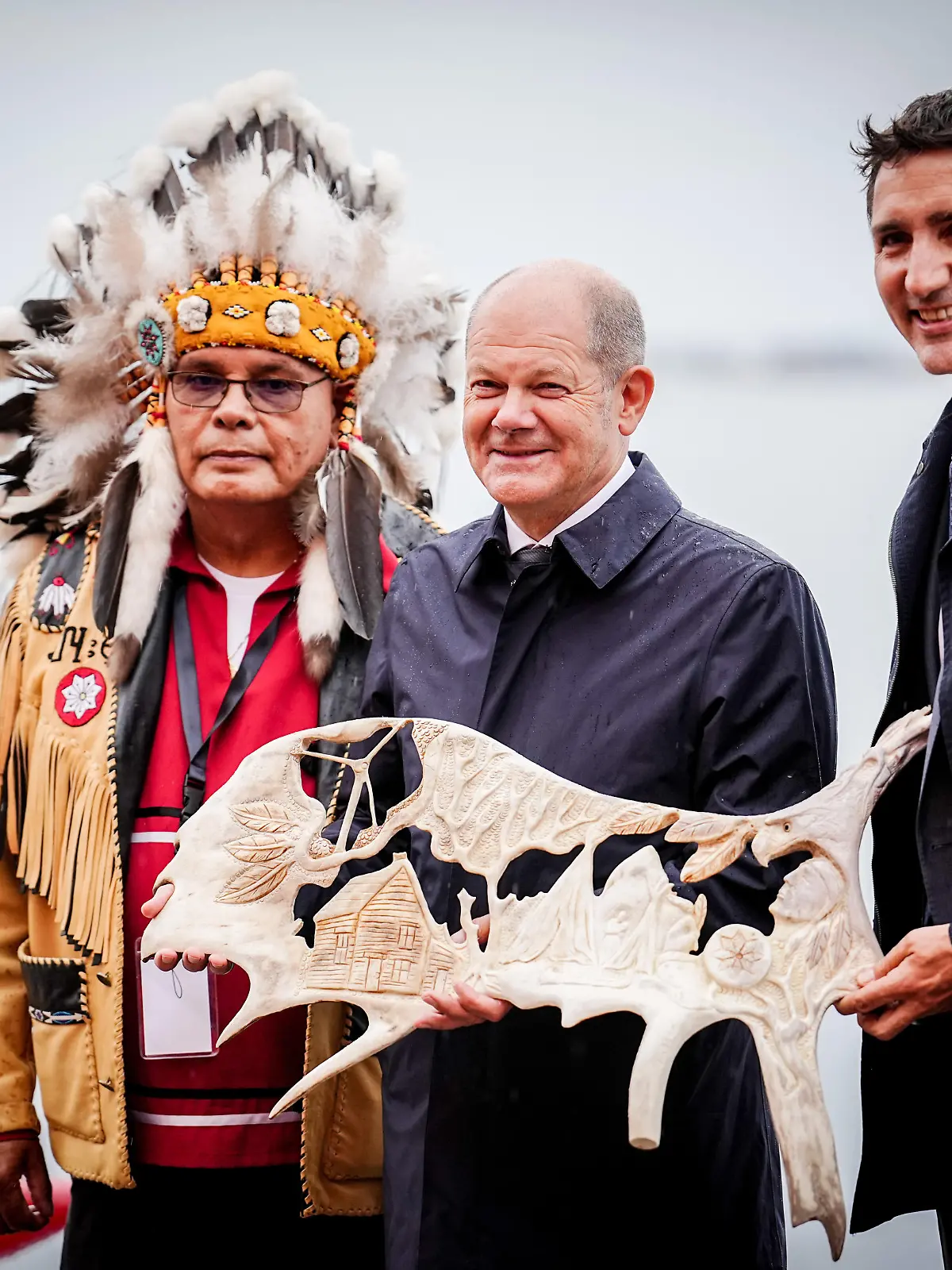 Bundeskanzler Olaf Scholz (M, SPD) und Justin Trudeau (r), Premierminister von Kanada, stehen mit Misel Joe, dem Chief der Ersten Nation Miawpukek, auf Neufundland mit einem verzierten Elchgeweih zusammen. Im Mittelpunkt der Reise steht die Zusammenarbeit beider Länder im Klima- und Energiebereich.
