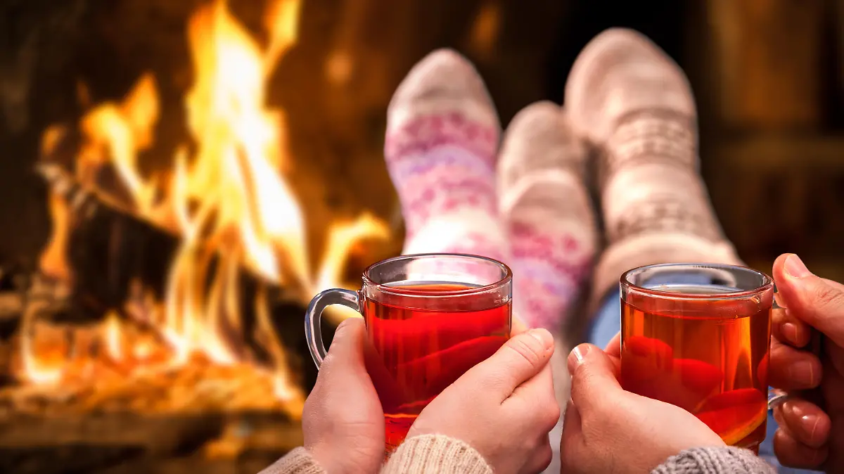 Couple relaxing with mulled wine at romantic fireplace on winter evening
