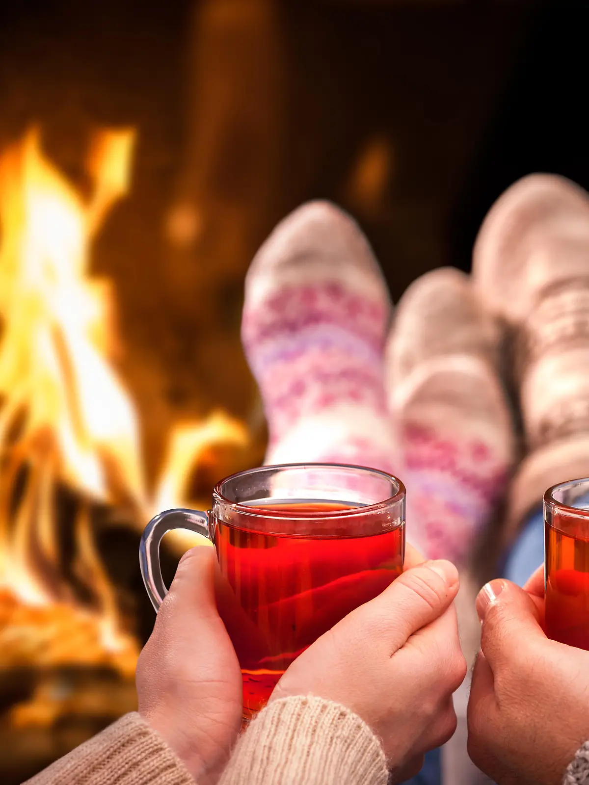 Couple relaxing with mulled wine at romantic fireplace on winter evening