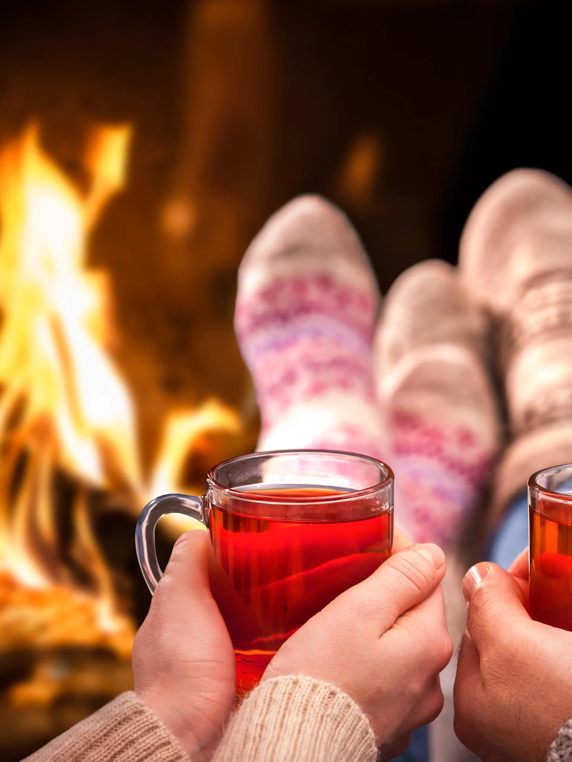 Couple relaxing with mulled wine at romantic fireplace on winter evening