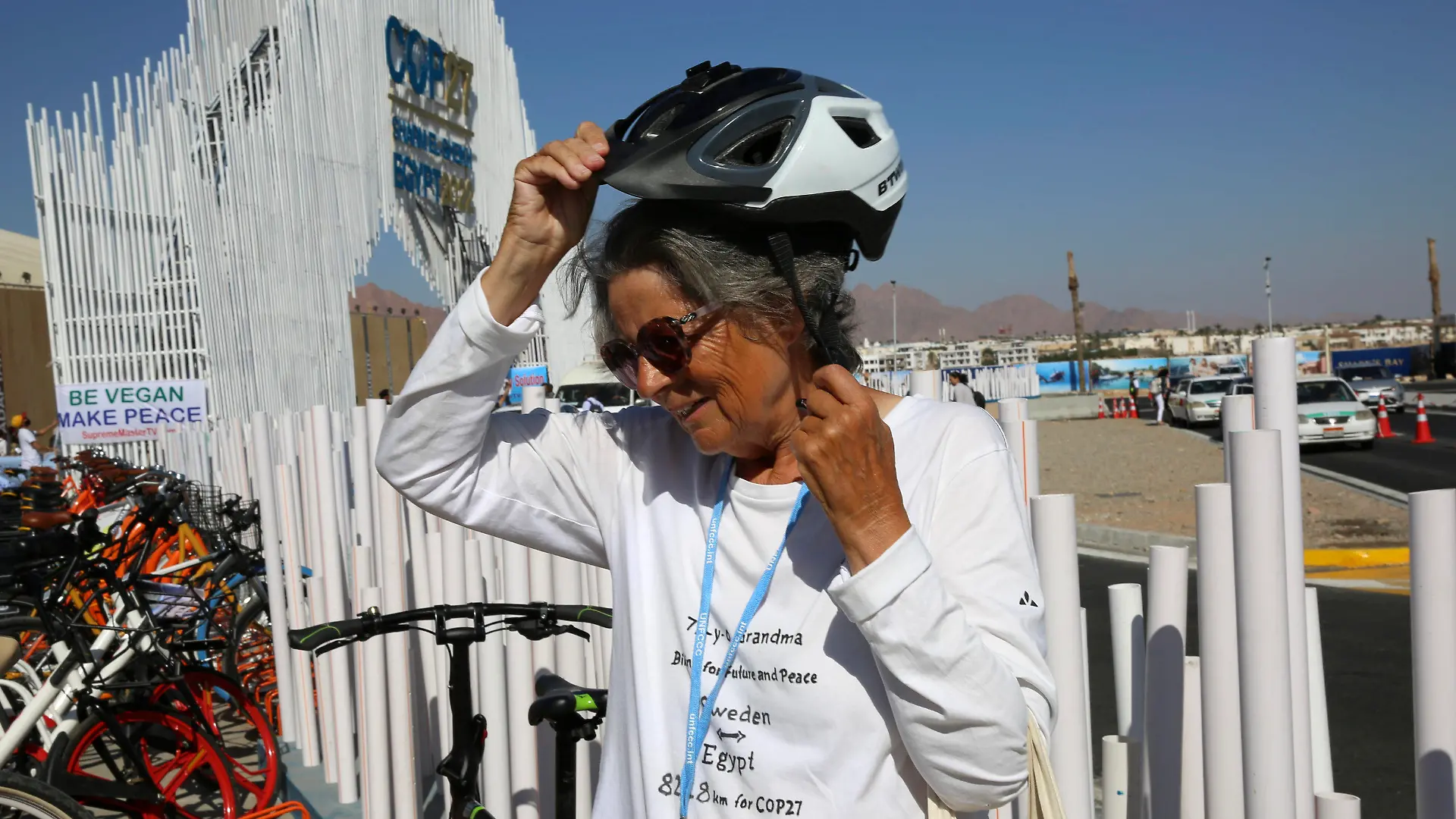 Dorothee Hildebrandt, 72, removes her bike helmet after arriving to the U.N. climate summit COP27 venue in Sharm el-Sheikh, Egypt, Saturday, Nov. 12, 2022. Hildebrandt biked from Sweden to Sharm el-Sheikh, Egypt, for COP27 to raise awareness and urge world leaders gathered at the conference to take concrete steps to stop climate change. (AP Photo/Thomas Hartwell)
