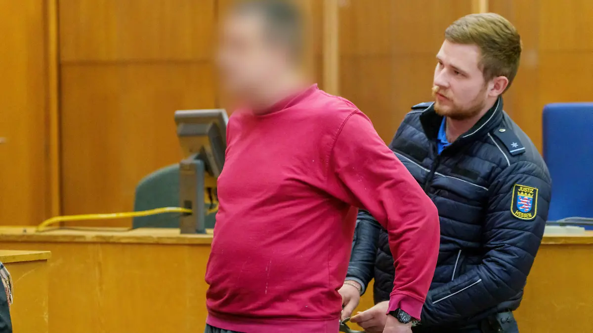 Fortsetzung im Prozess um die "NSU 2.0"-Drohschreiben am Donnerstag (17.11.2022) in Frankfurt am Main. (Foto: Dem Angeklagten (l.) werden die Handschellen abgenommen) In dem Prozess muss sich ein Mann aus Berlin wegen Beleidigung, Bedrohung und Noetigung verantworten. Er ist der mutmassliche Verfasser der NSU 2.0-Drohschreiben gegen Politikerinnen, Rechtsanwaelte und Personen des oeffentlichen Lebens. (Siehe epd-Meldung vom 17.11.2022)