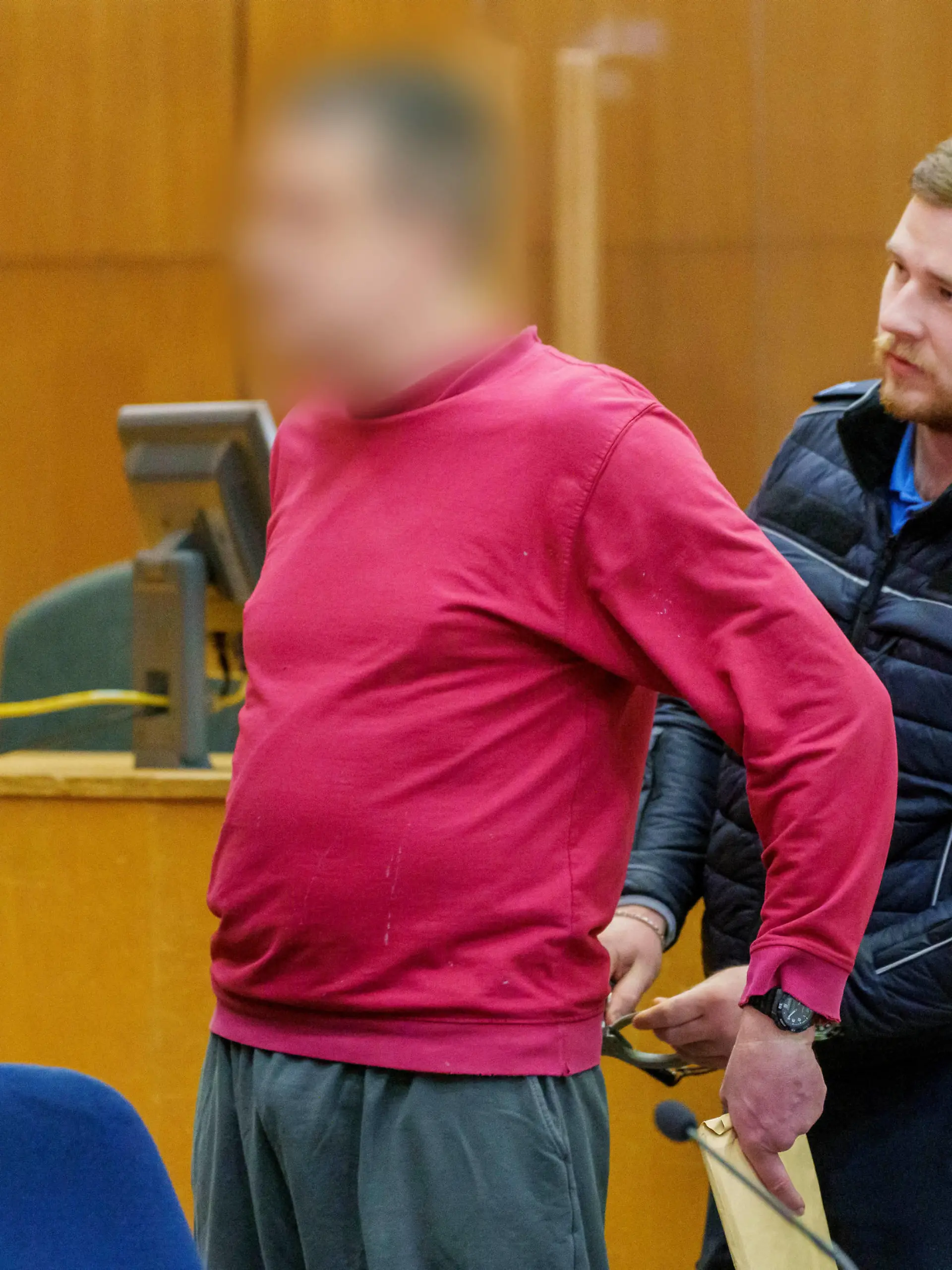 Fortsetzung im Prozess um die "NSU 2.0"-Drohschreiben am Donnerstag (17.11.2022) in Frankfurt am Main. (Foto: Dem Angeklagten (l.) werden die Handschellen abgenommen) In dem Prozess muss sich ein Mann aus Berlin wegen Beleidigung, Bedrohung und Noetigung verantworten. Er ist der mutmassliche Verfasser der NSU 2.0-Drohschreiben gegen Politikerinnen, Rechtsanwaelte und Personen des oeffentlichen Lebens. (Siehe epd-Meldung vom 17.11.2022)