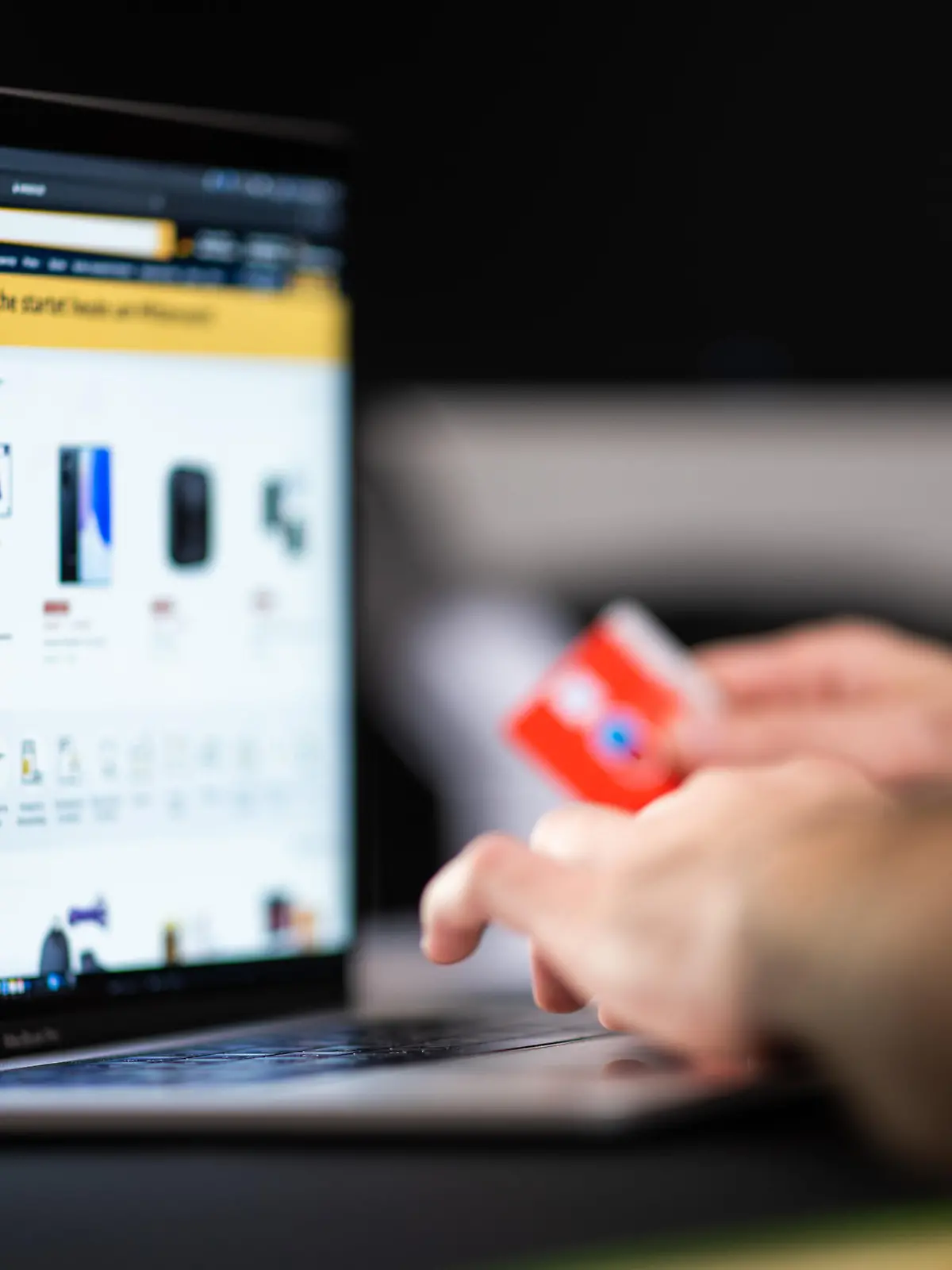 Ein Mann mit einer Bankkarte in der Hand sitzt am Laptop und schaut sich die Black Friday Angebote auf der Online-Shopping-Seite von Amazon an. (zu dpa „Trotz Lieferengpässen: Black Friday lockt Schnäppchenjäger“)