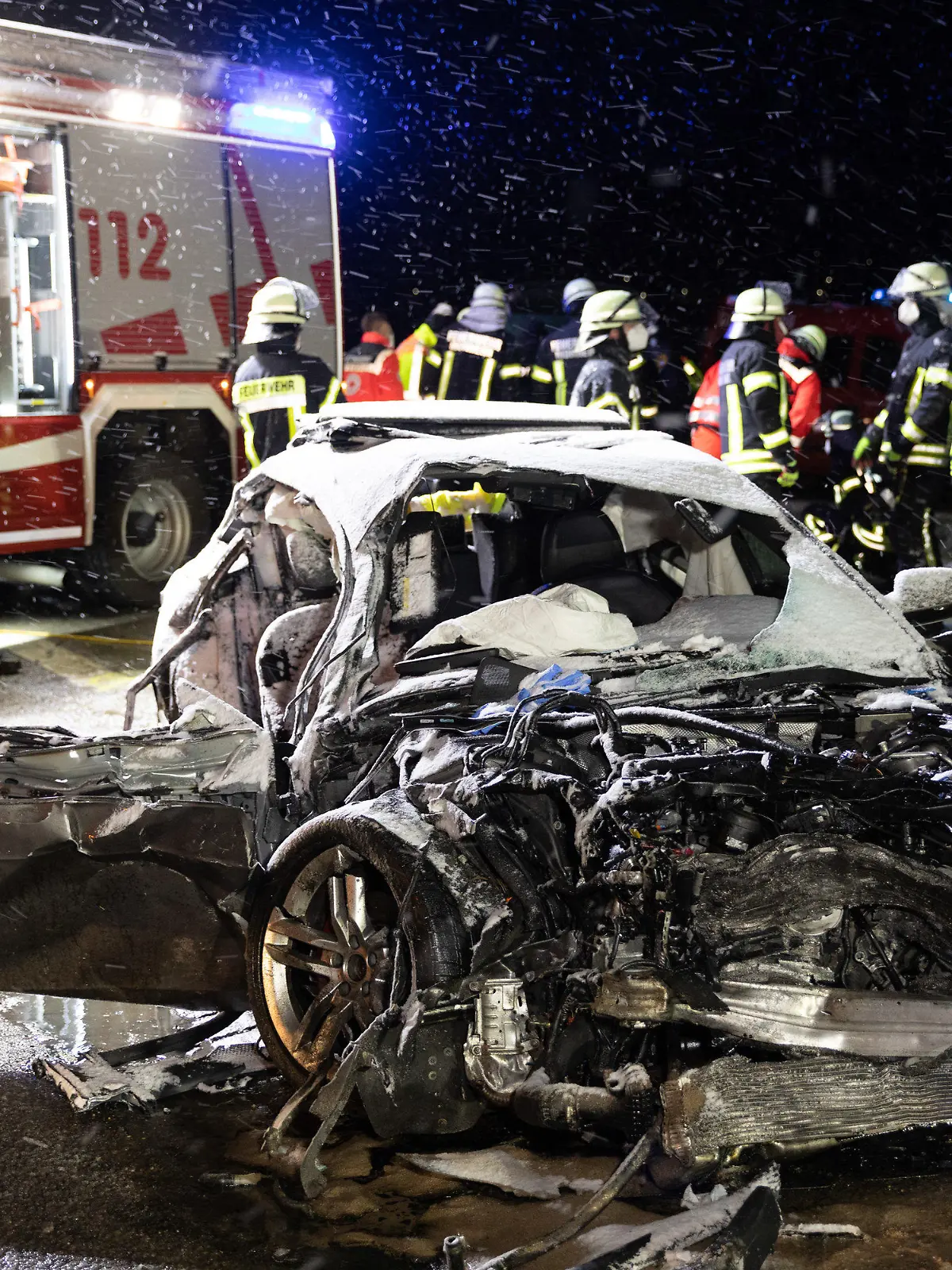 ARCHIV - 06.04.2021, Donau-Ries, Monheim: Feuerwehrleute stehen an einer Unfallstelle hinter einem Autowrack. Eine 54 Jahre alte Frau ist noch am Unfallort gestorben, nachdem ein Autofahrer frontal mit seinem Wagen in ihr Fahrzeug gefahren war. Der 28 Jahre alte Autofahrer muss sich wegen eines verbotenen Autorennens vor dem Landgericht Augsburg verantworten, nachdem er etwa doppelt so schnell wie erlaubt gefahren ist und die Kontrolle über seinen Wagen verloren hat. Am Donnerstag will das Gericht das Urteil verkünden. (zu dpa «Gericht verkündet nach tödlichem Raserunfall Urteil») Foto: Ralph Goppelt/vifogra/dpa +++ dpa-Bildfunk +++