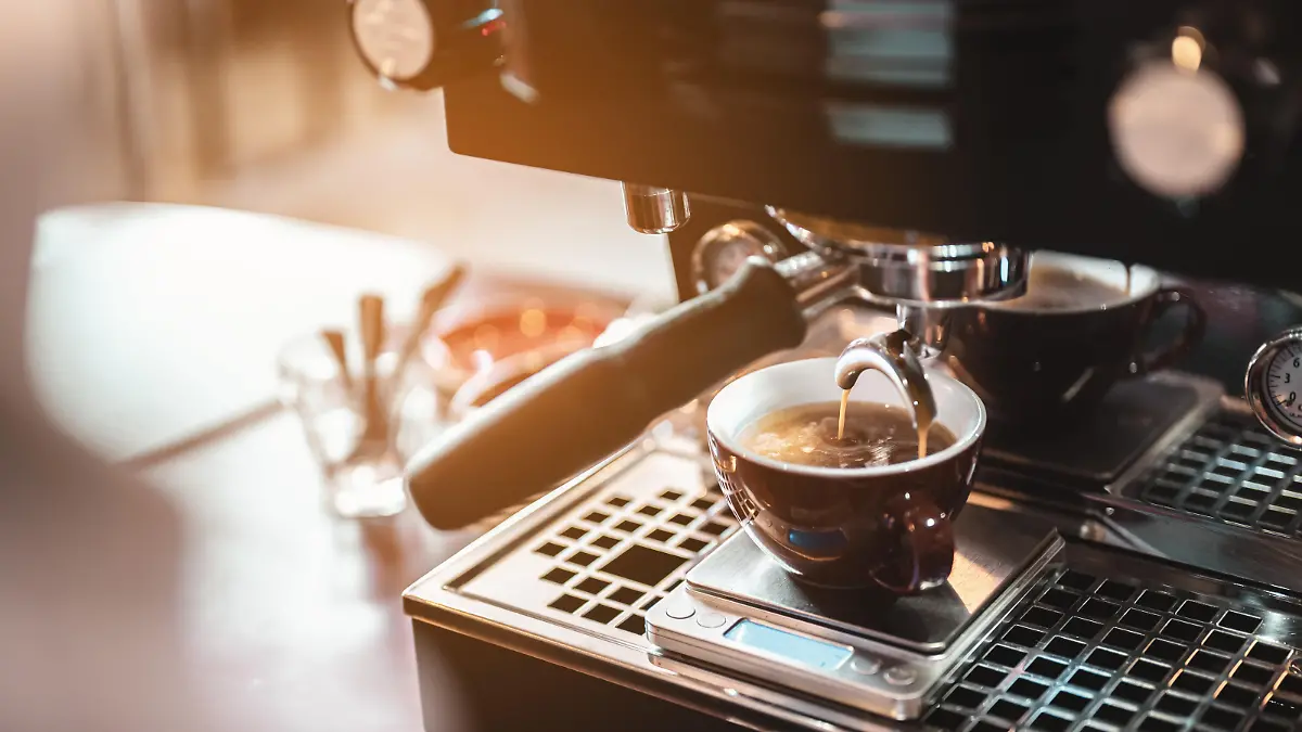 Close-up coffee maker that is professionally extracting coffee by barista with a deep white glass in the evening sun light. coffee, extraction, deep, machine, make, barista concept.