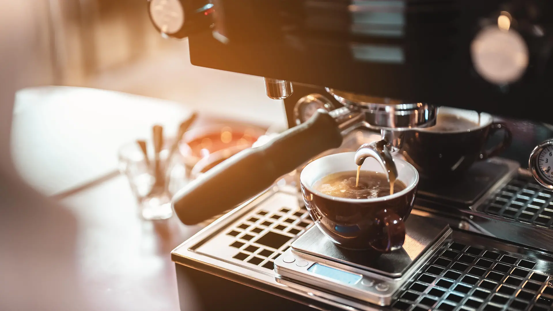 Close-up coffee maker that is professionally extracting coffee by barista with a deep white glass in the evening sun light. coffee, extraction, deep, machine, make, barista concept.