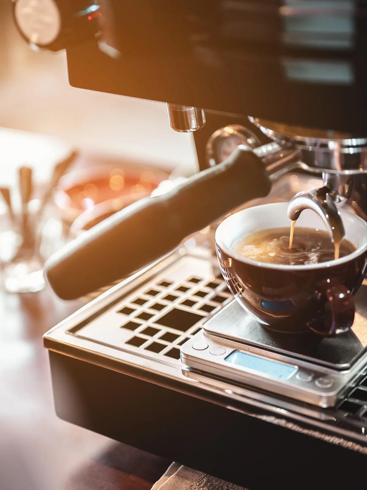 Close-up coffee maker that is professionally extracting coffee by barista with a deep white glass in the evening sun light. coffee, extraction, deep, machine, make, barista concept.