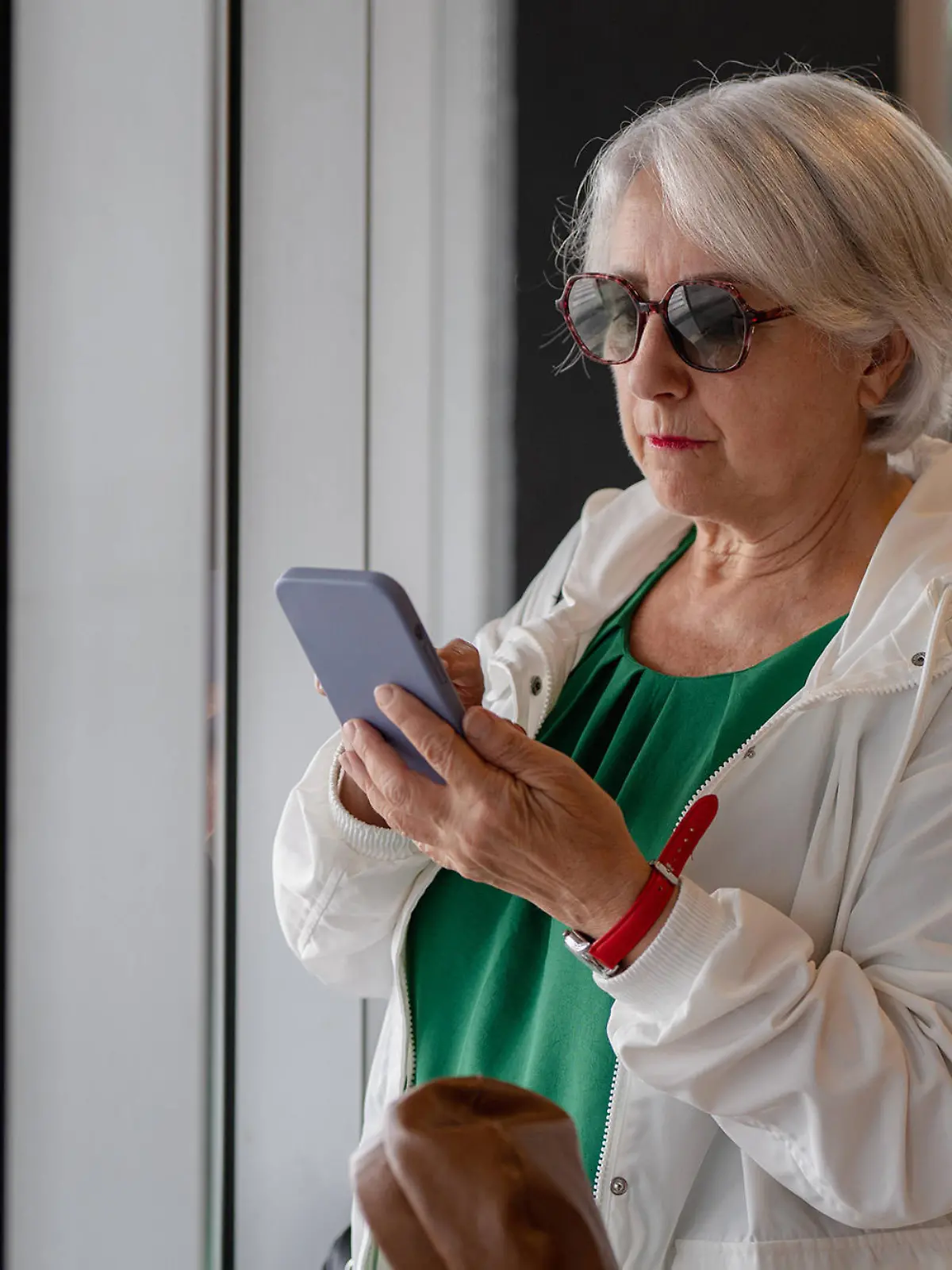 MR_ID14379_13537_MariasunMuNoz.jpg Focused aged lady with short gray hair in sunglasses surfing internet on smartphone while standing near window, Model released HodeiUnzueta_ID14379_431670_004 Copyright: xHodeixUnzuetax