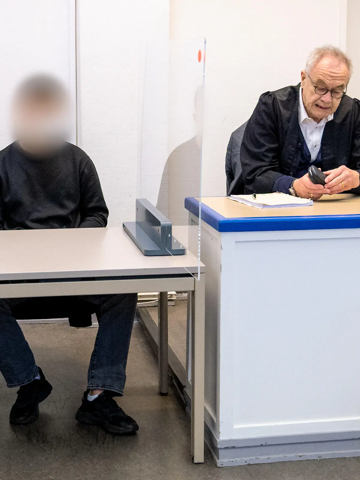 16.11.2022, Hamburg: Ein 22 Jahre alter Angeklagter (l.) sitzt im Amtsgericht Harburg im Saal neben seinem Anwalt Siegfried Schäfer. Der Mann soll auf einer Party im Stadtteil Winterhude einem 16-jährigen Mädchen zwei Ecstasy-Tabletten gegeben haben, das Mädchen starb kurz danach an einer von den Drogen ausgelösten Hyperthermie (Überwärmung). Foto: Daniel Bockwoldt/dpa - ACHTUNG: Person wurde aus rechtlichen Gründen gepixelt +++ dpa-Bildfunk +++