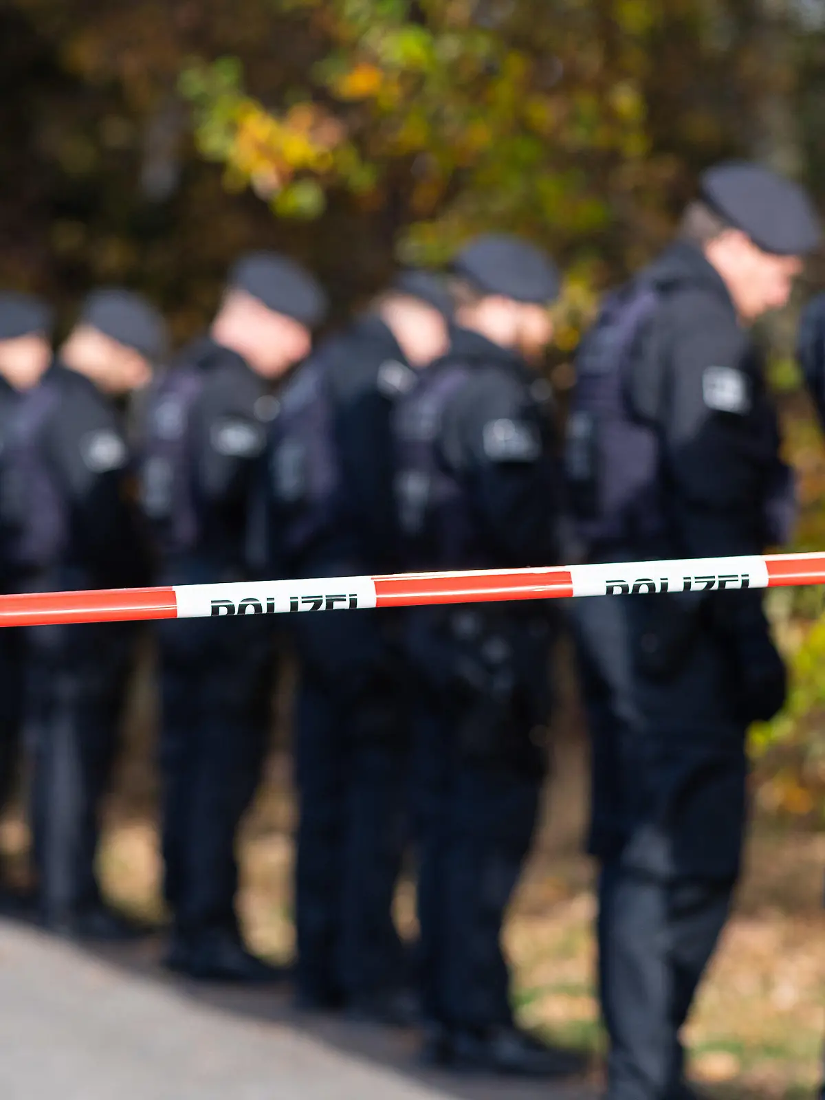 15.11.2022, Nordrhein-Westfalen, Ostbevern: Polizisten hinter einem Polizeiabsperrband durchsuchen das Gelände, in dem am Morgen eine 13jährige bewusstlos aufgefunden worden war. Das 13-jähriges Mädchen war in Ostbevern im Münsterland auf dem Weg zur Schule offenbar unter nicht näher bekannten Umständen angegriffen worden. Das Mädchen sei von einem Passanten bewusstlos am Boden liegend gefunden und vom Rettungsdienst in ein Krankenhaus gebracht worden, sagte eine Polizeisprecherin. Foto: Guido Kirchner/dpa +++ dpa-Bildfunk +++