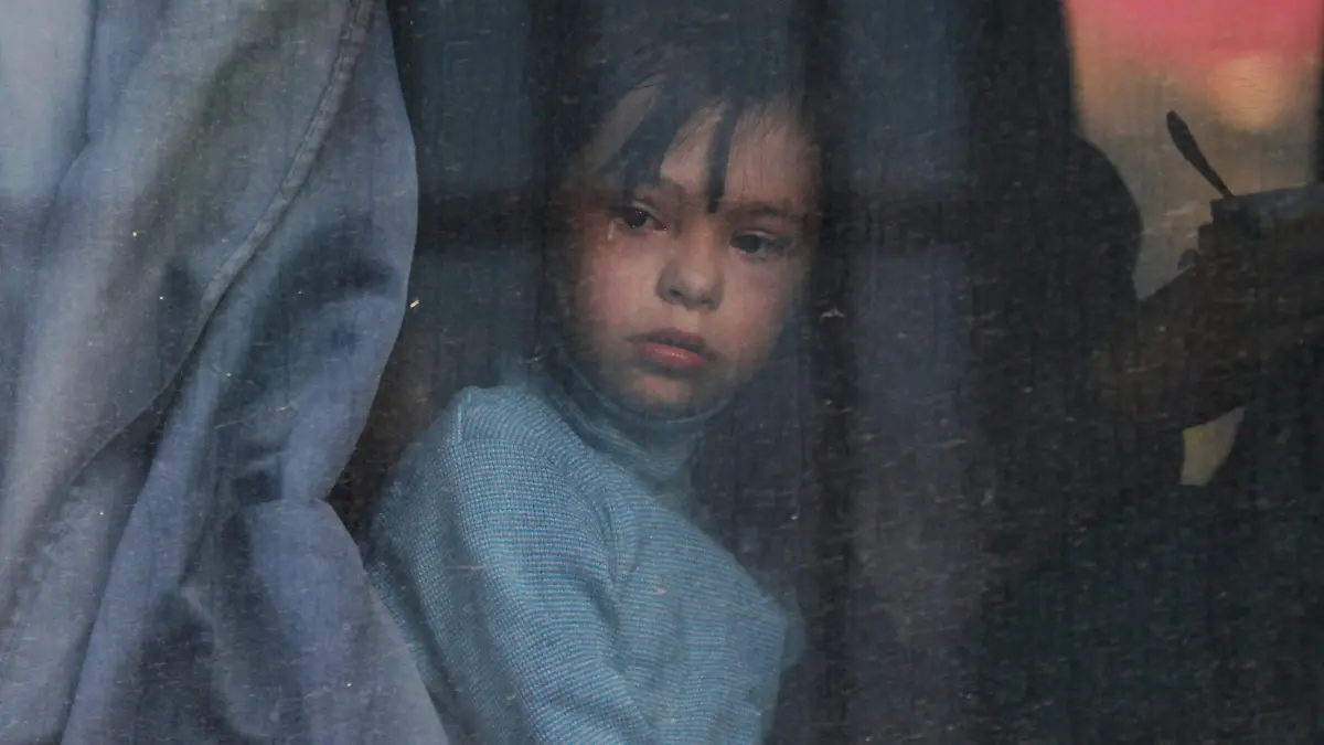 A child looks out of a bus window as civilians evacuated from the Russian-controlled Kherson region of Ukraine arrive at a local railway station, after Russian-installed officials extended an evacuation order to the area along the eastern bank of the Dnipro River, in the town of Dzhankoi, Crimea November 2, 2022. REUTERS/Alexey Pavlishak