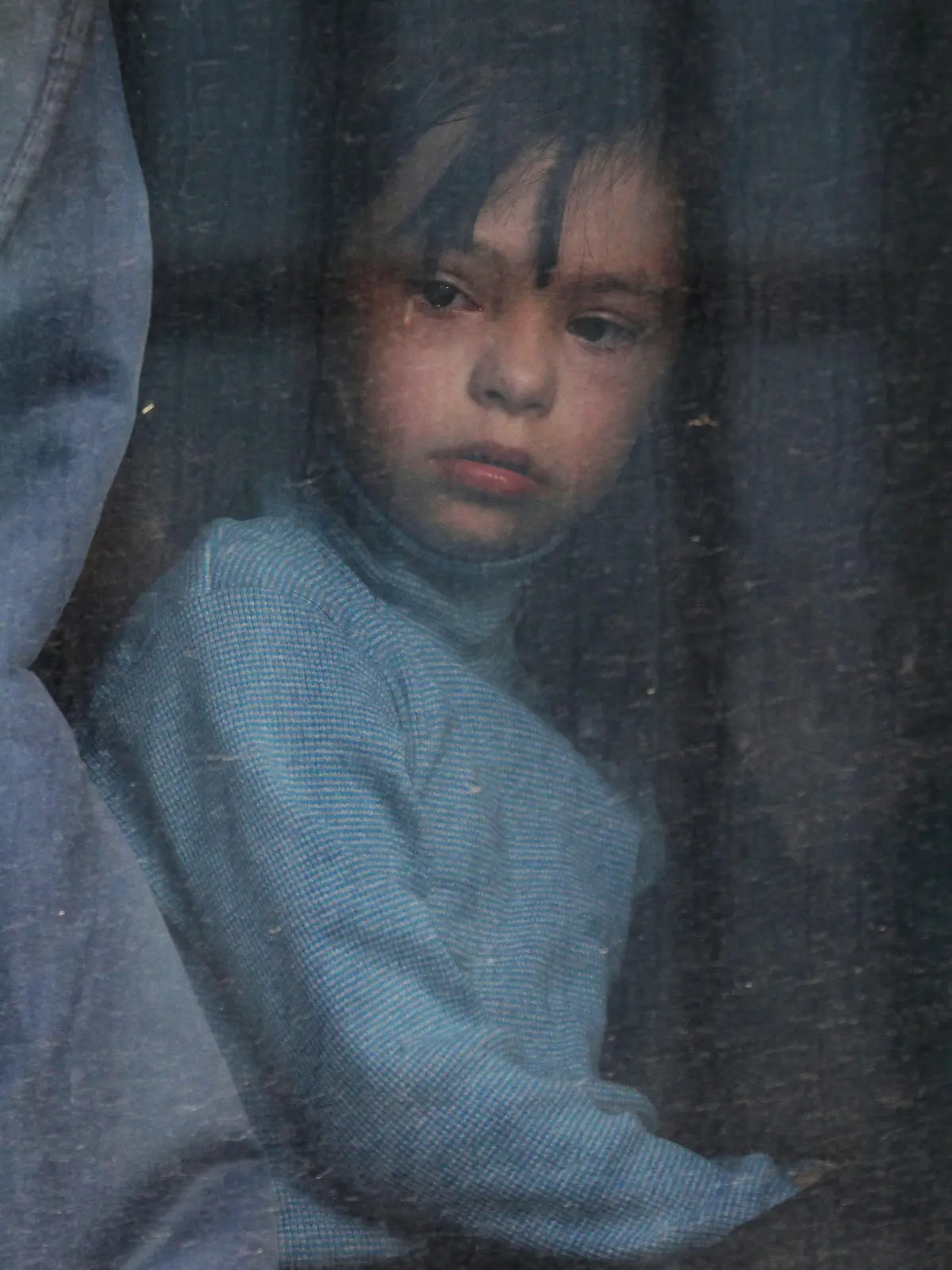 A child looks out of a bus window as civilians evacuated from the Russian-controlled Kherson region of Ukraine arrive at a local railway station, after Russian-installed officials extended an evacuation order to the area along the eastern bank of the Dnipro River, in the town of Dzhankoi, Crimea November 2, 2022. REUTERS/Alexey Pavlishak