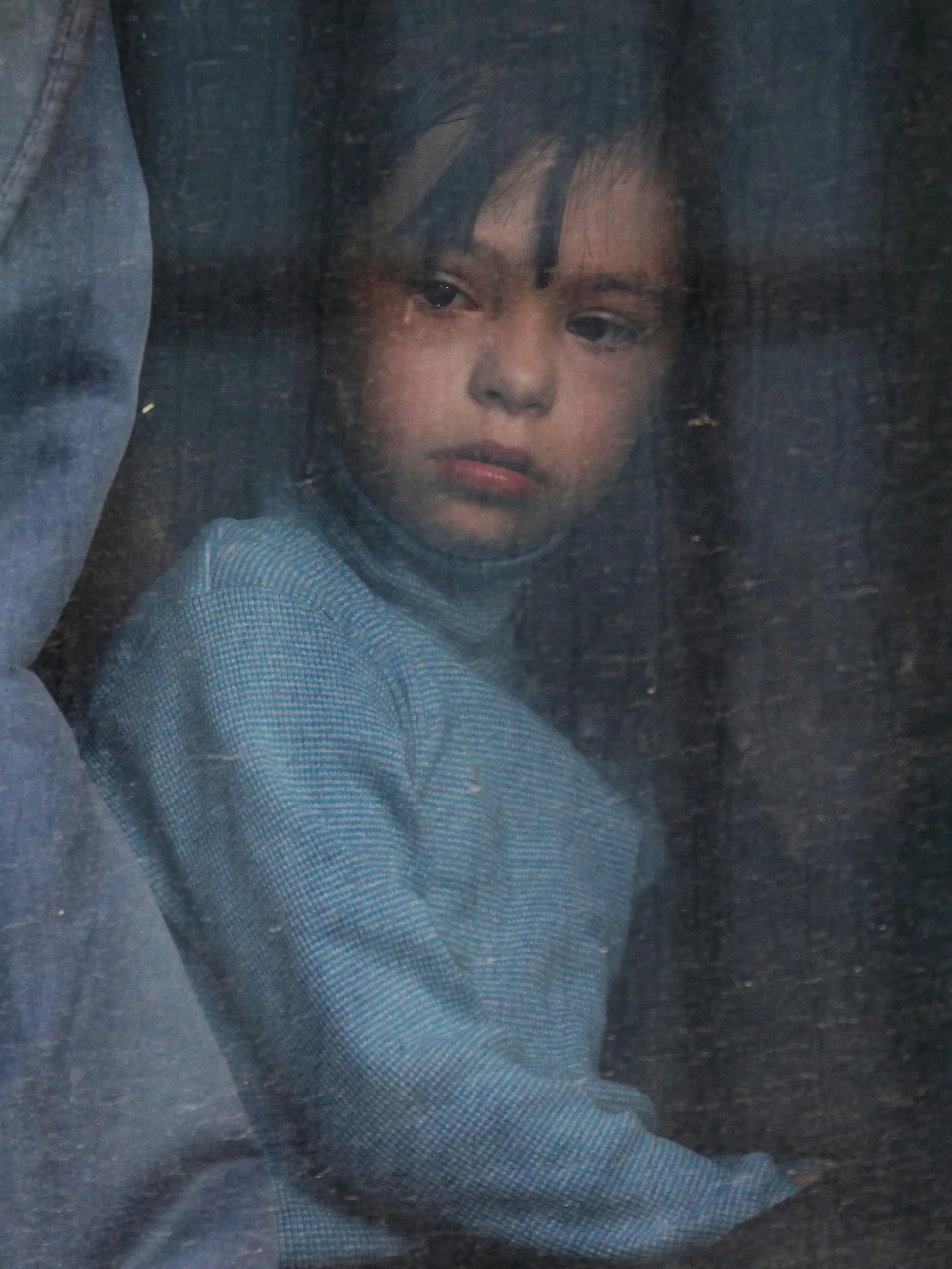 A child looks out of a bus window as civilians evacuated from the Russian-controlled Kherson region of Ukraine arrive at a local railway station, after Russian-installed officials extended an evacuation order to the area along the eastern bank of the Dnipro River, in the town of Dzhankoi, Crimea November 2, 2022. REUTERS/Alexey Pavlishak