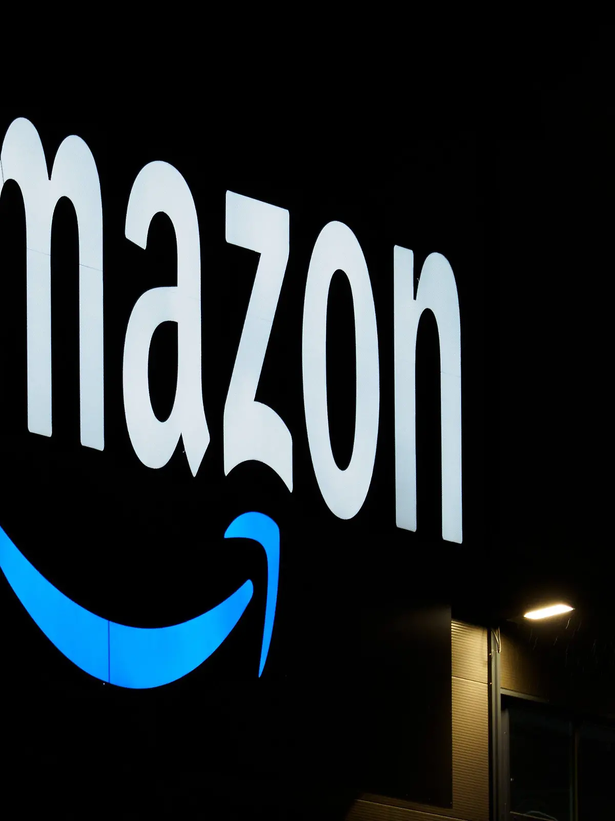 ARCHIV - 17.12.2020, Brandenburg, Schönefeld: Das Logo von Amazon ist am einem Logistikzentrum des Onlineversandhändlers zu sehen. Der weltgrößte Online-Versandhändler Amazon plant US-Medienberichten zufolge angesichts des trüben Wirtschaftsausblicks seinen bislang größten Jobabbau. Der Konzern wolle noch diese Woche mit der Streichung von rund 10 000 Stellen beginnen, schrieb die «New York Times» am Montag unter Berufung auf Insider. (zu dpa: "US-Medien: Amazon will Tausende Stellen streichen") Foto: Soeren Stache/dpa-Zentralbild/dpa +++ dpa-Bildfunk +++