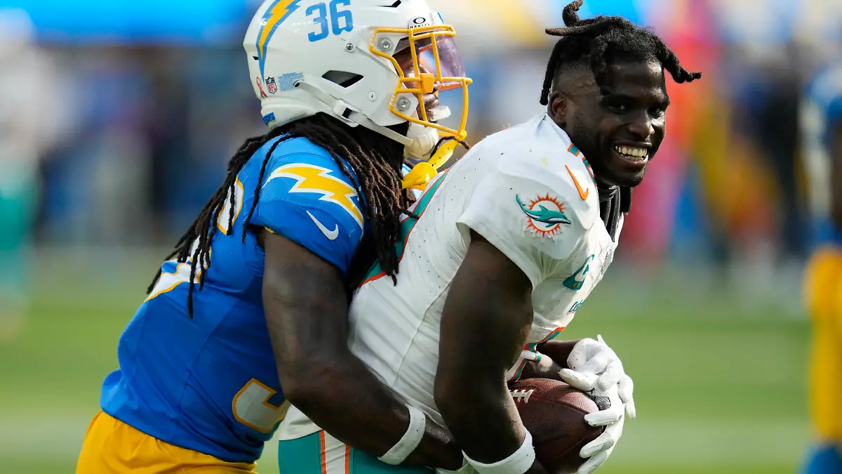 Miami Dolphins wide receiver Tyreek Hill (10) loses his helmet after making a catch next to Los Angeles Chargers cornerback Ja'Sir Taylor during the second half of an NFL football game Sunday, Sept. 10, 2023, in Inglewood, Calif. (AP Photo/Ashley Landis)