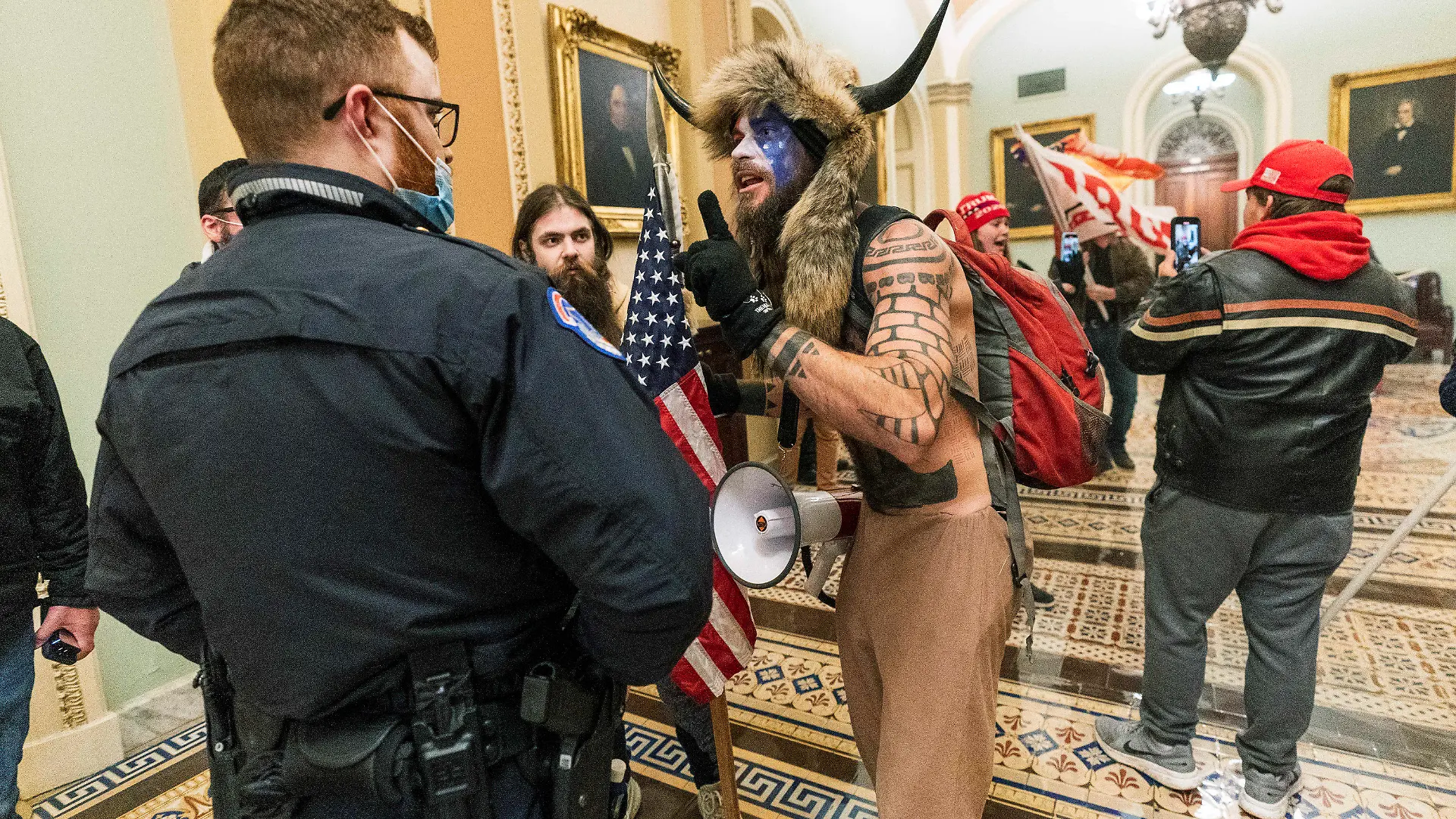 ARCHIV - 06.01.2021, USA, Washington: Unterstützer von US-Präsident Trump stehen auf dem Gang vor der Senatskammer im US-Kapitol und bedrängen einen Polizisten (l), während Anhänger des dmalaigen US-Präsidneten Trump das Kapitol stürmen. Der frühere US-Präsident Trump wehrt sich auf juristischem Weg gegen seine Vorladung durch den Untersuchungsausschuss zum Angriff auf das Kapitol. (zu dpa "Trump klagt gegen Vorladung durch U-Ausschuss zu Kapitol-Attacke") Foto: Manuel Balce Ceneta/AP/dpa +++ dpa-Bildfunk +++