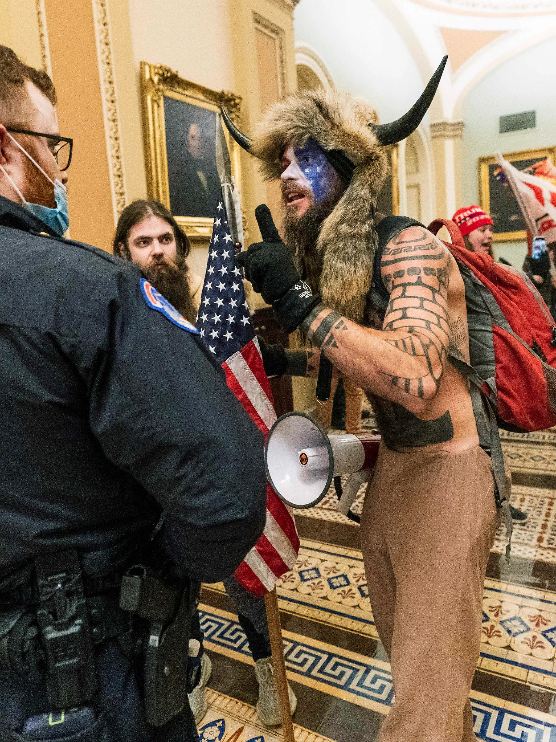 ARCHIV - 06.01.2021, USA, Washington: Unterstützer von US-Präsident Trump stehen auf dem Gang vor der Senatskammer im US-Kapitol und bedrängen einen Polizisten (l), während Anhänger des dmalaigen US-Präsidneten Trump das Kapitol stürmen. Der frühere US-Präsident Trump wehrt sich auf juristischem Weg gegen seine Vorladung durch den Untersuchungsausschuss zum Angriff auf das Kapitol. (zu dpa "Trump klagt gegen Vorladung durch U-Ausschuss zu Kapitol-Attacke") Foto: Manuel Balce Ceneta/AP/dpa +++ dpa-Bildfunk +++