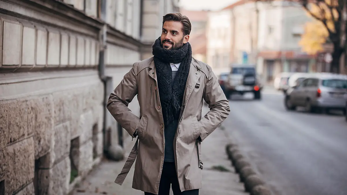 One young handsome man dressed in warm winter clothing walking on the city street.